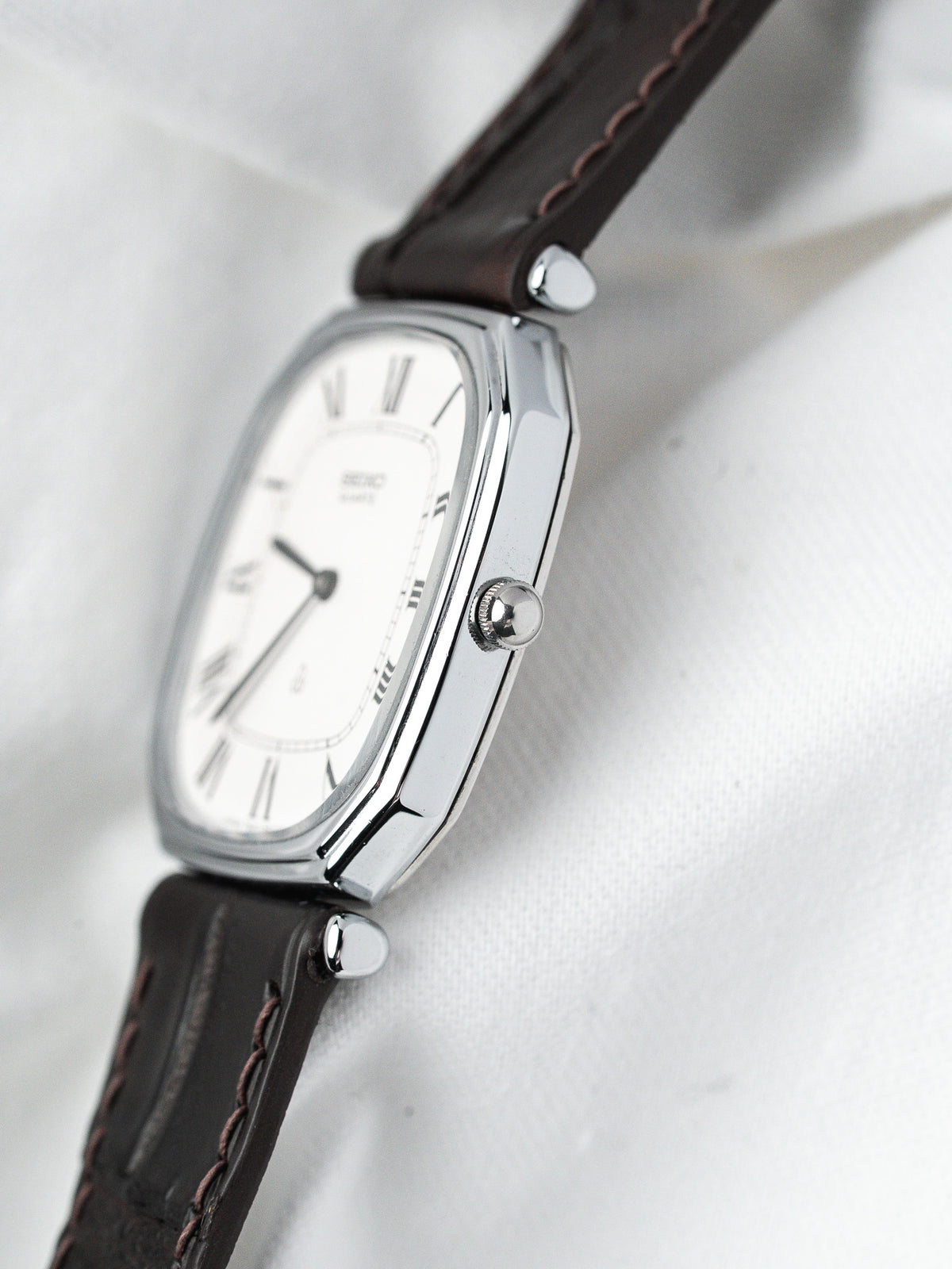 Montre Seiko vintage, boîtier rectangulaire argenté, cadran blanc et bracelet en cuir marron