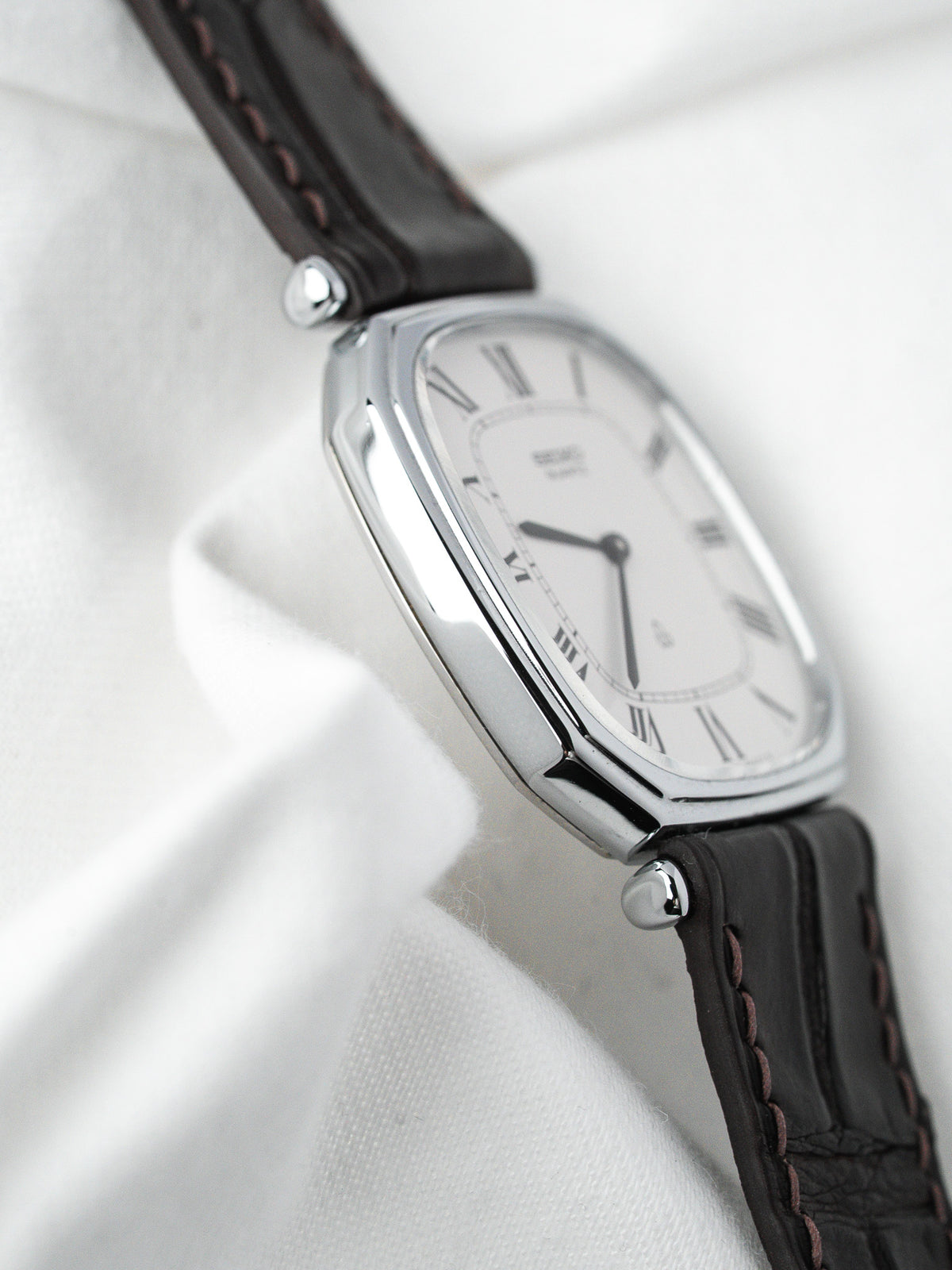 Montre vintage au boîtier rectangulaire argenté, cadran blanc et bracelet en cuir marron