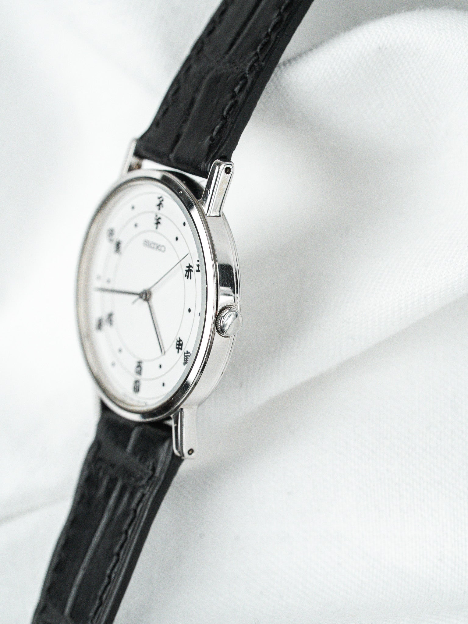 Seiko vintage watch with white dial, black leather strap, and Japanese characters on face