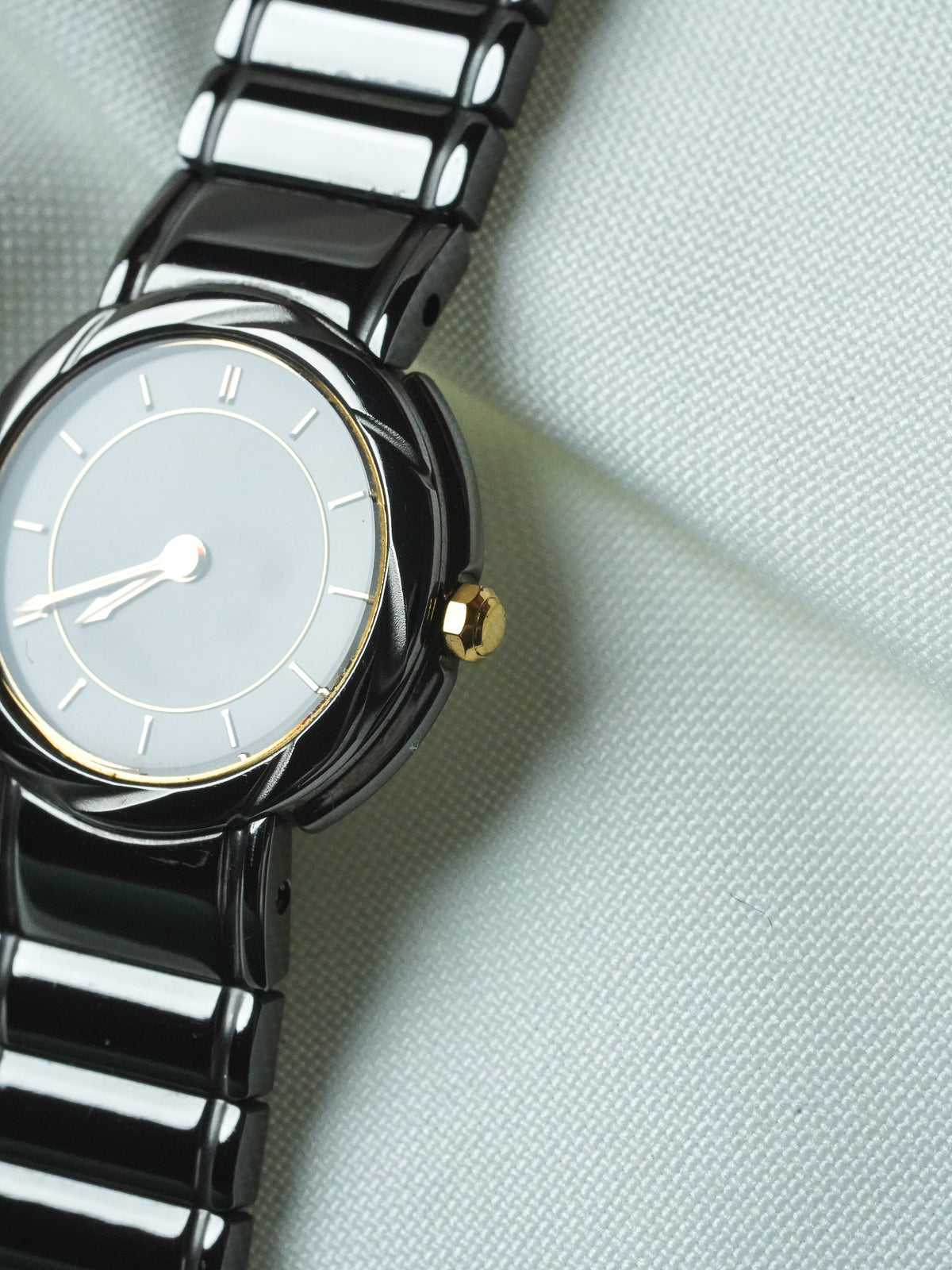 Vintage Cartier watch with black ceramic bracelet, grey dial, gold accents on textured fabric