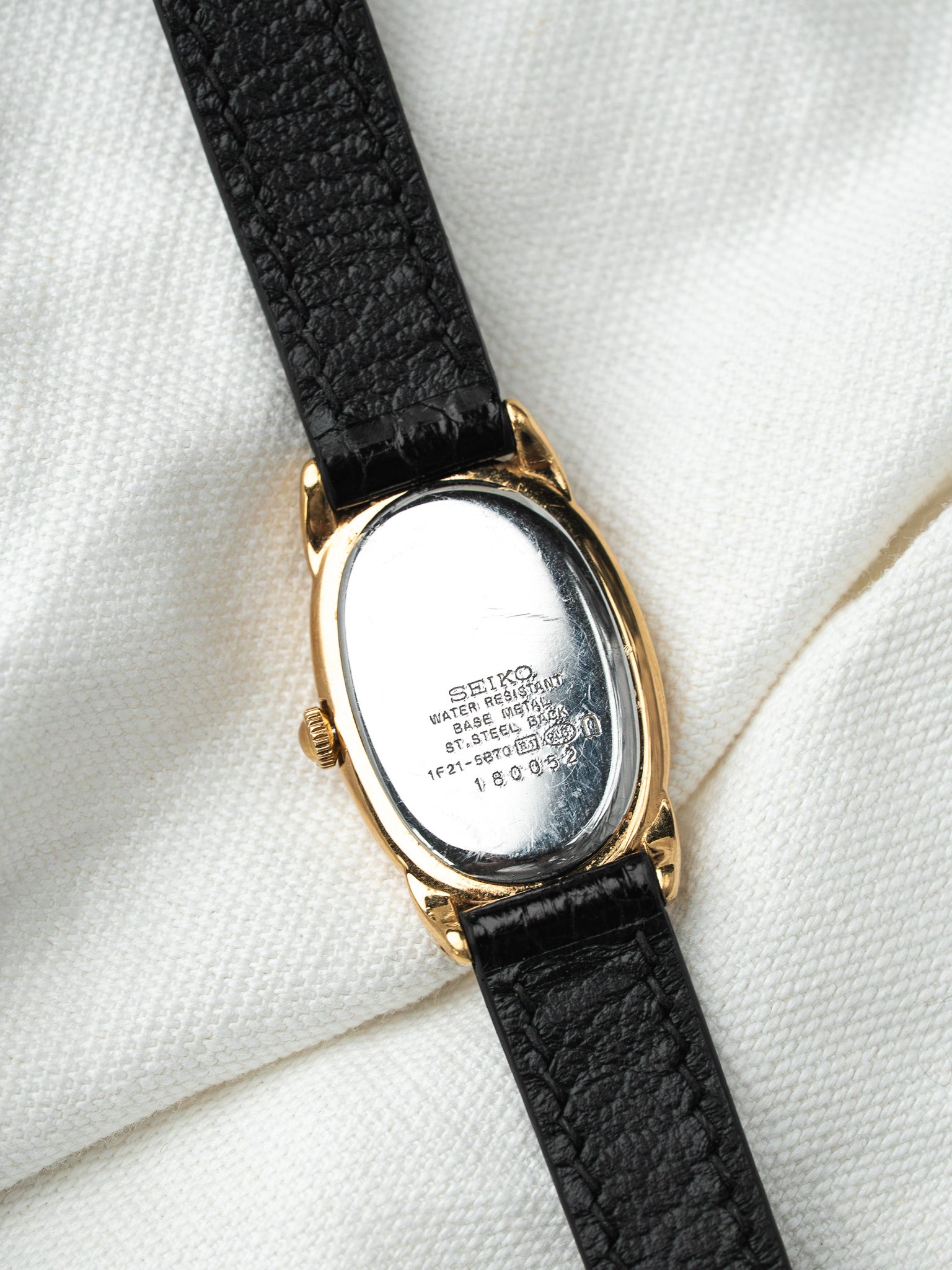 Seiko vintage watch with gold case, black leather strap, steel back engraved