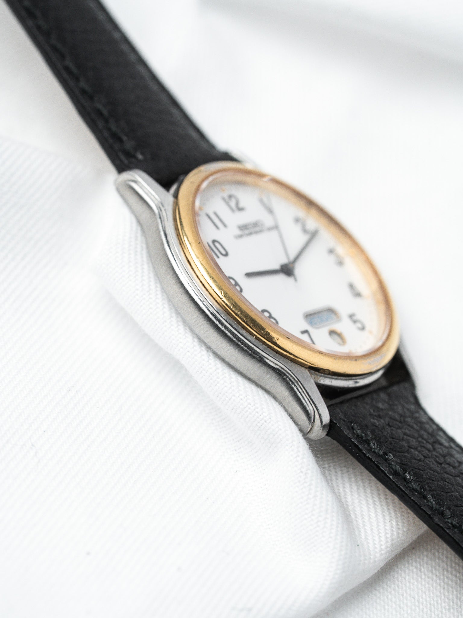 ساعة Seiko فينتاج ثنائي اللون — يوم-تاريخ قرص أبيض (ثمانينيات القرن العشرين)
