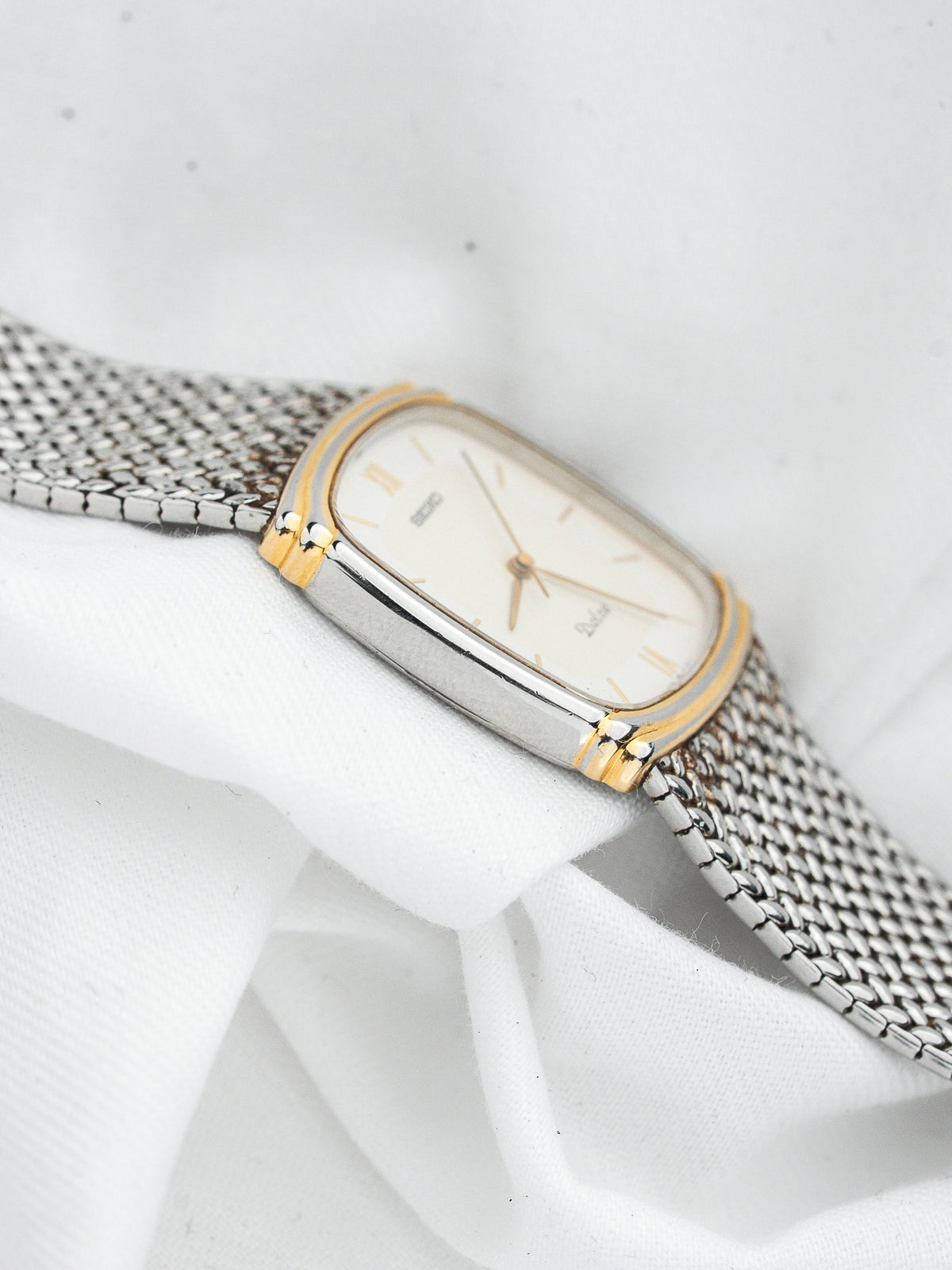 Montre Seiko vintage, boîtier rectangulaire bicolore et bracelet en acier mailles milanaises