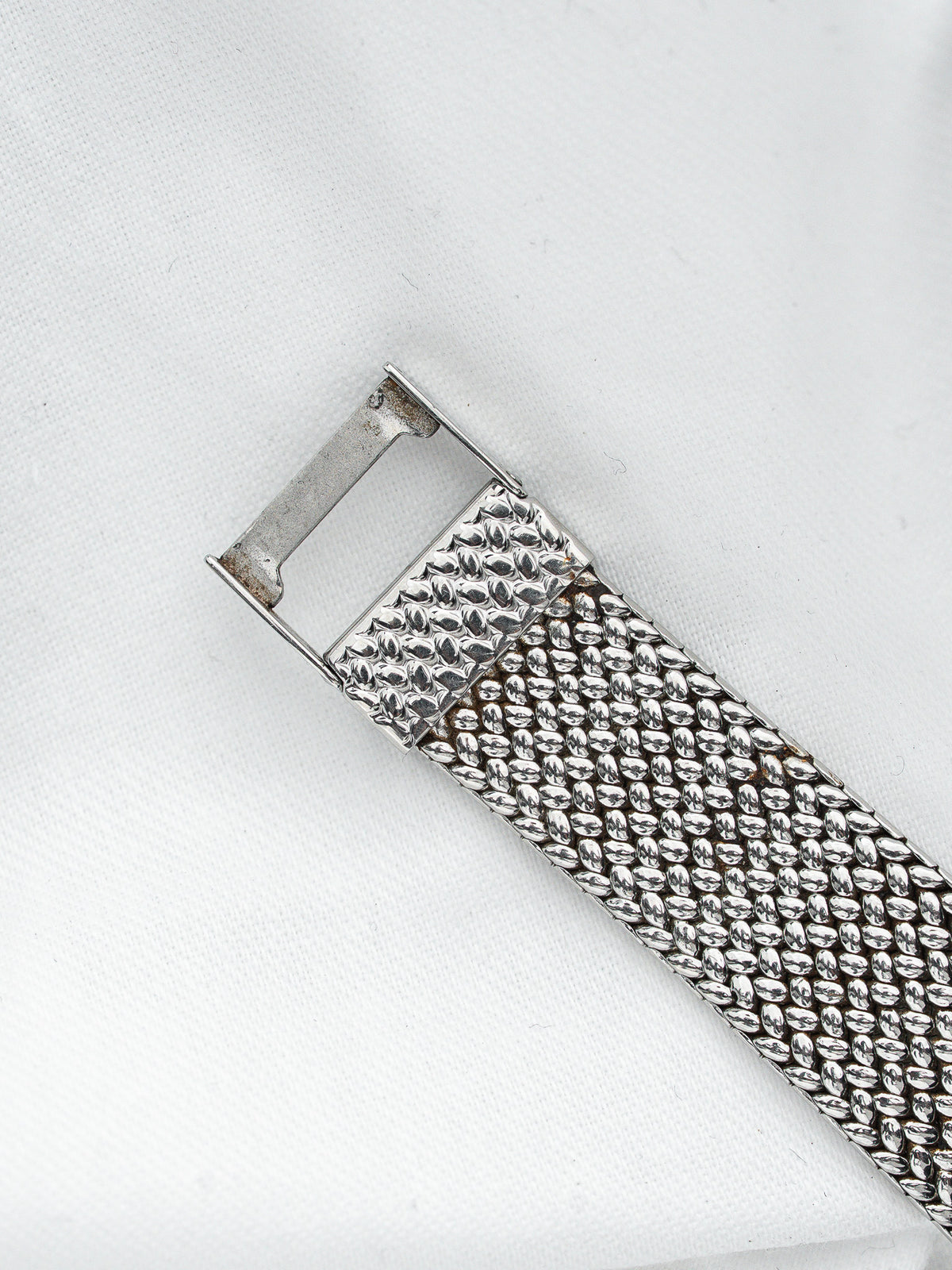 Bracelet de montre vintage en maille milanaise argentée sur fond blanc