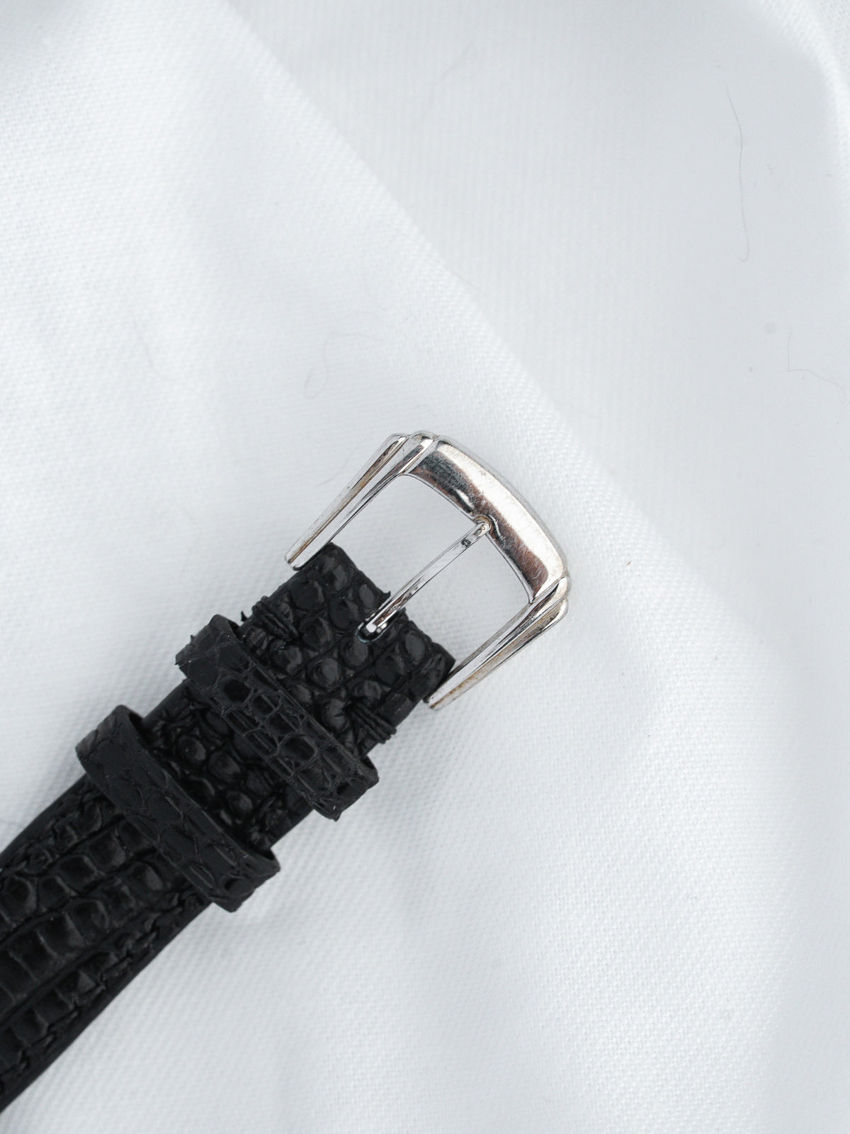 Black alligator leather watch strap with silver buckle on white background
