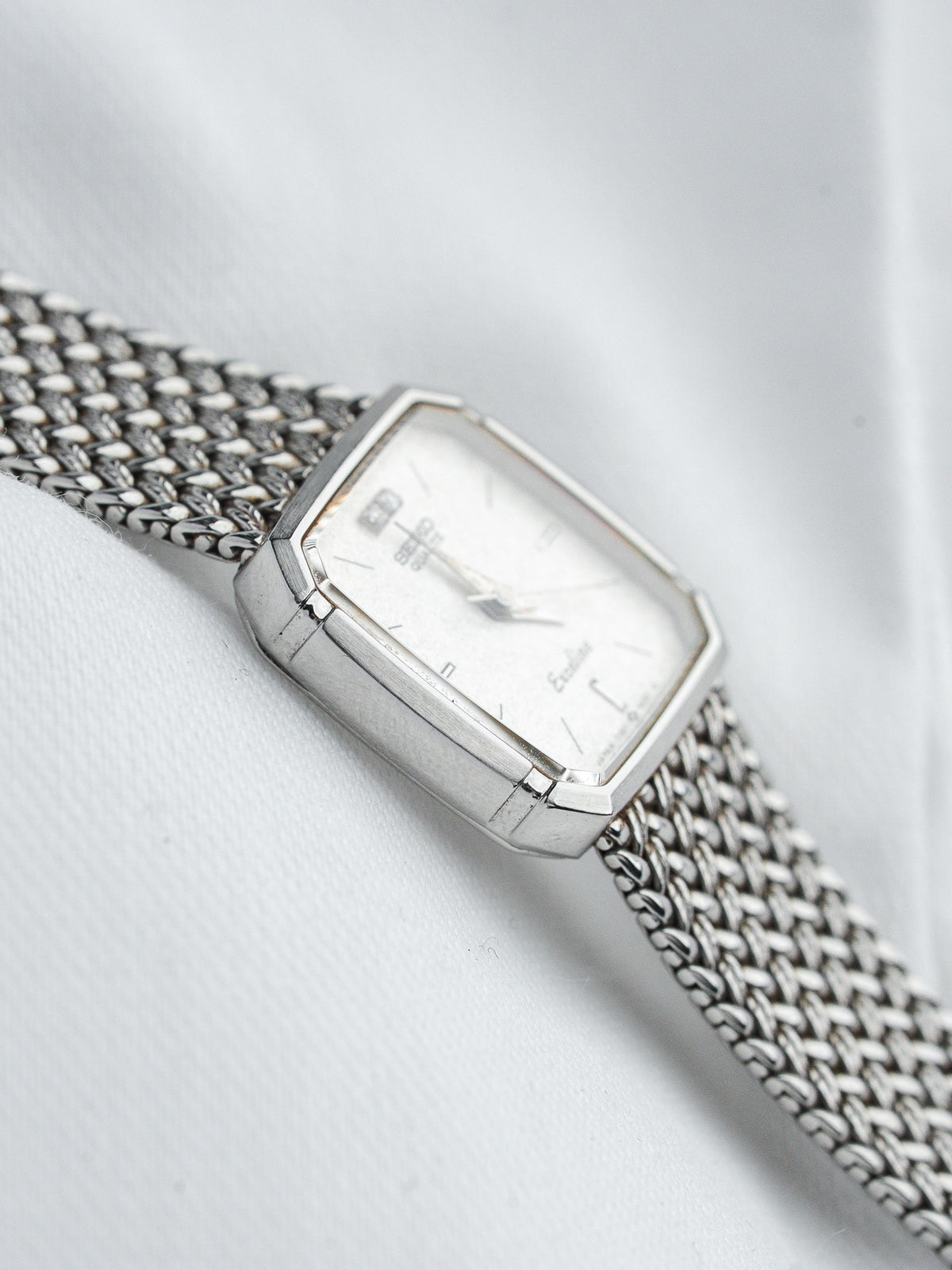 Ebel vintage watch with white dial, silver case, and mesh bracelet on fabric