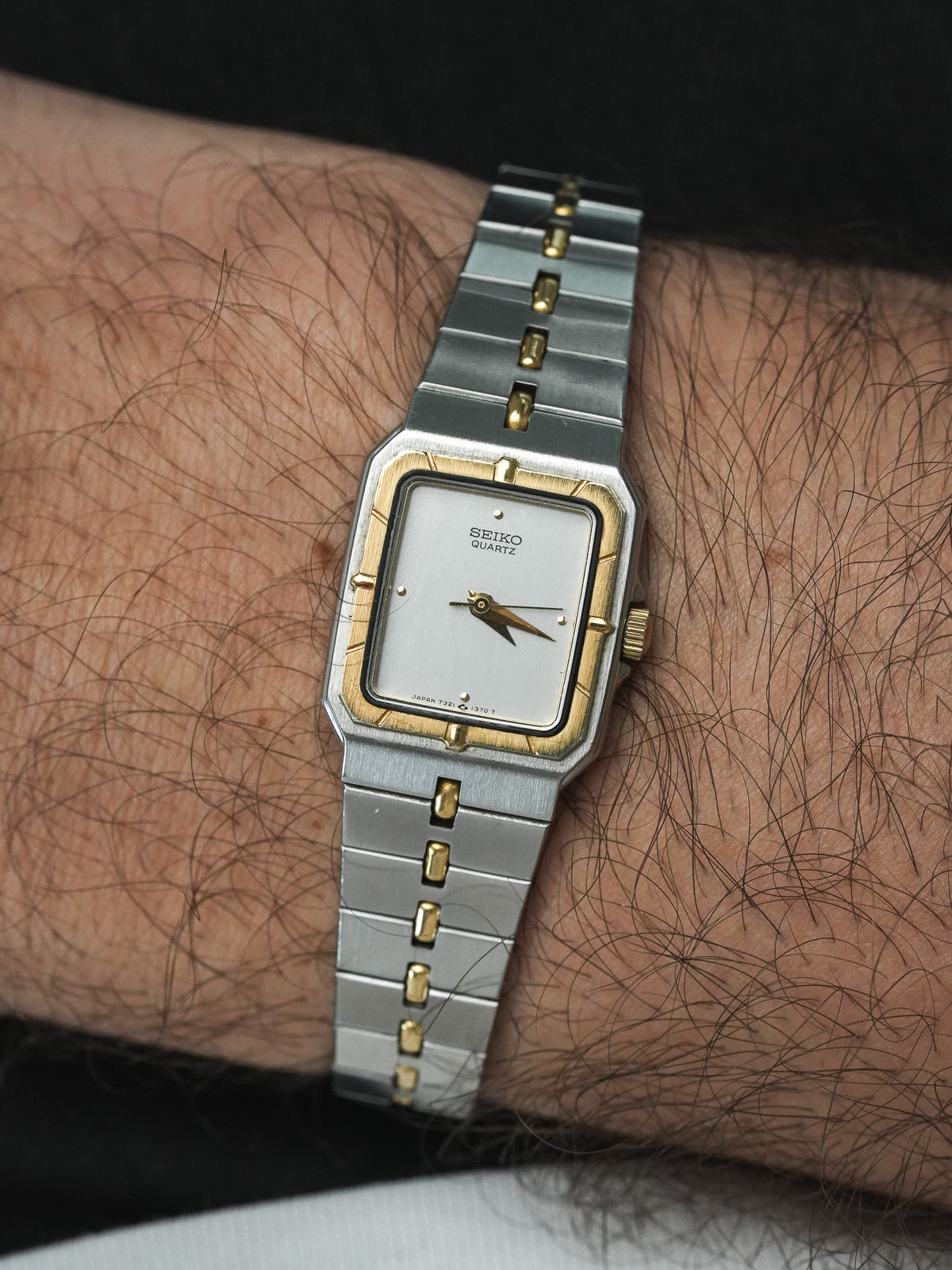 Seiko Quartz vintage watch with silver and gold case, white dial, worn on wrist