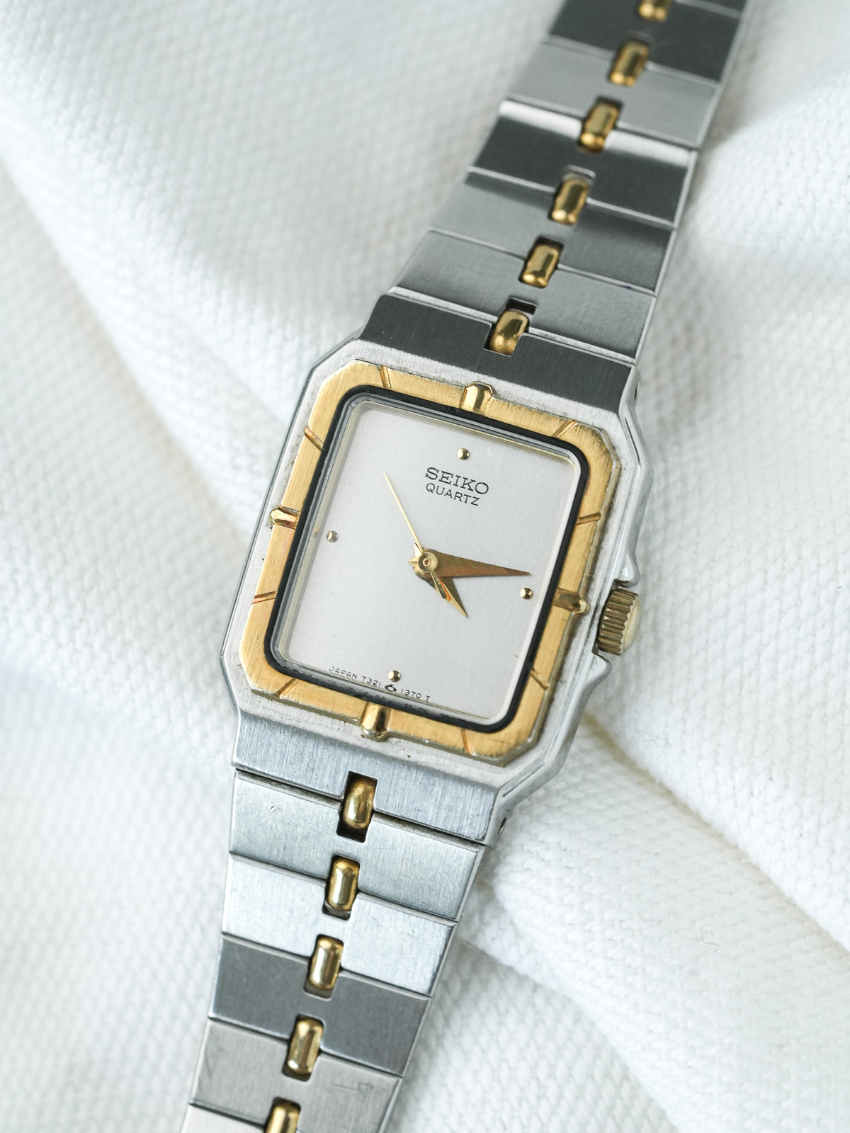 Seiko Quartz vintage watch with silver and gold-tone case, white dial, on white fabric