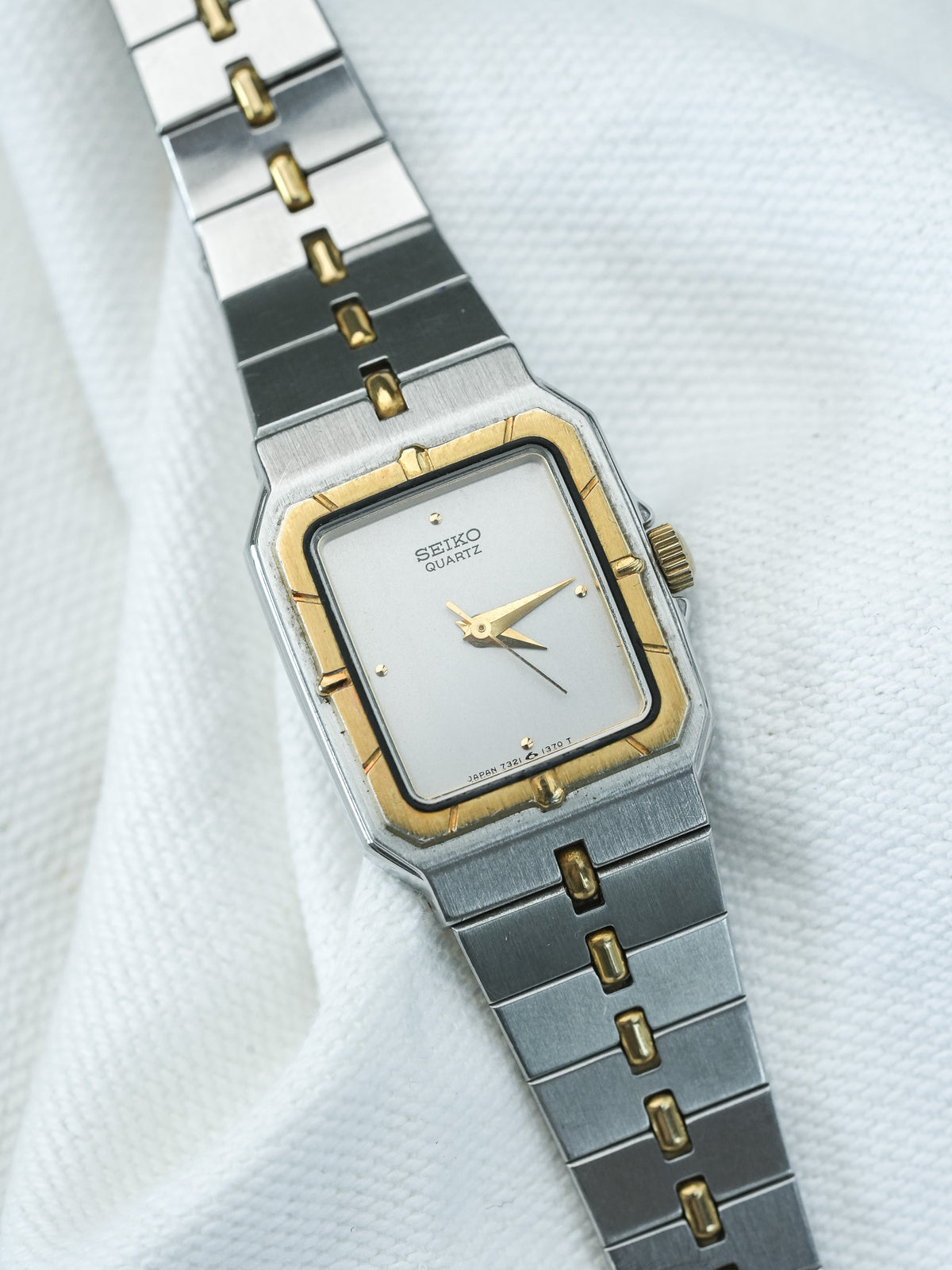 Seiko Quartz vintage watch with two-tone steel and gold bracelet, silver dial on white fabric