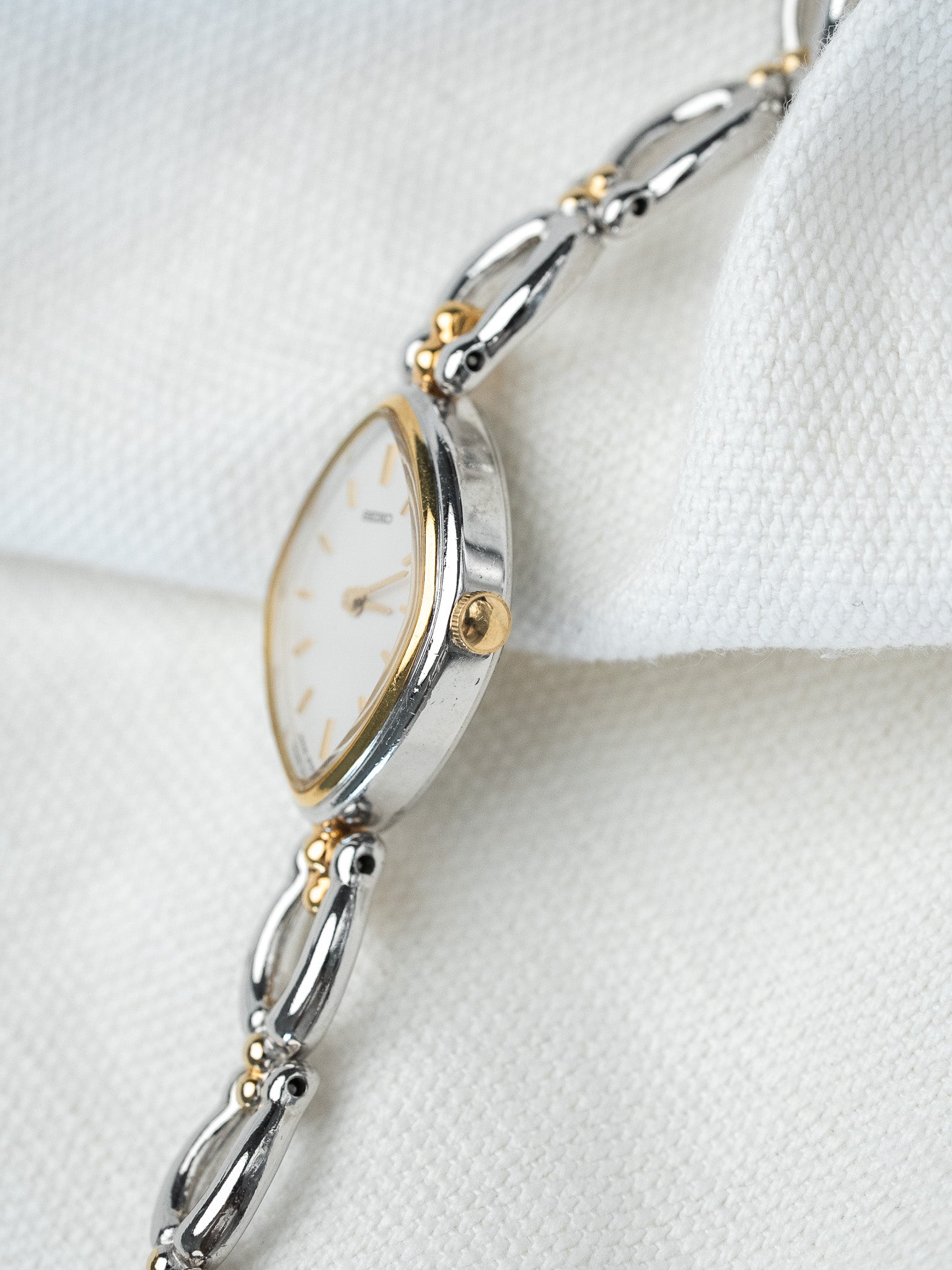 Seiko vintage watch with two-tone bracelet, white dial, gold accents on white fabric
