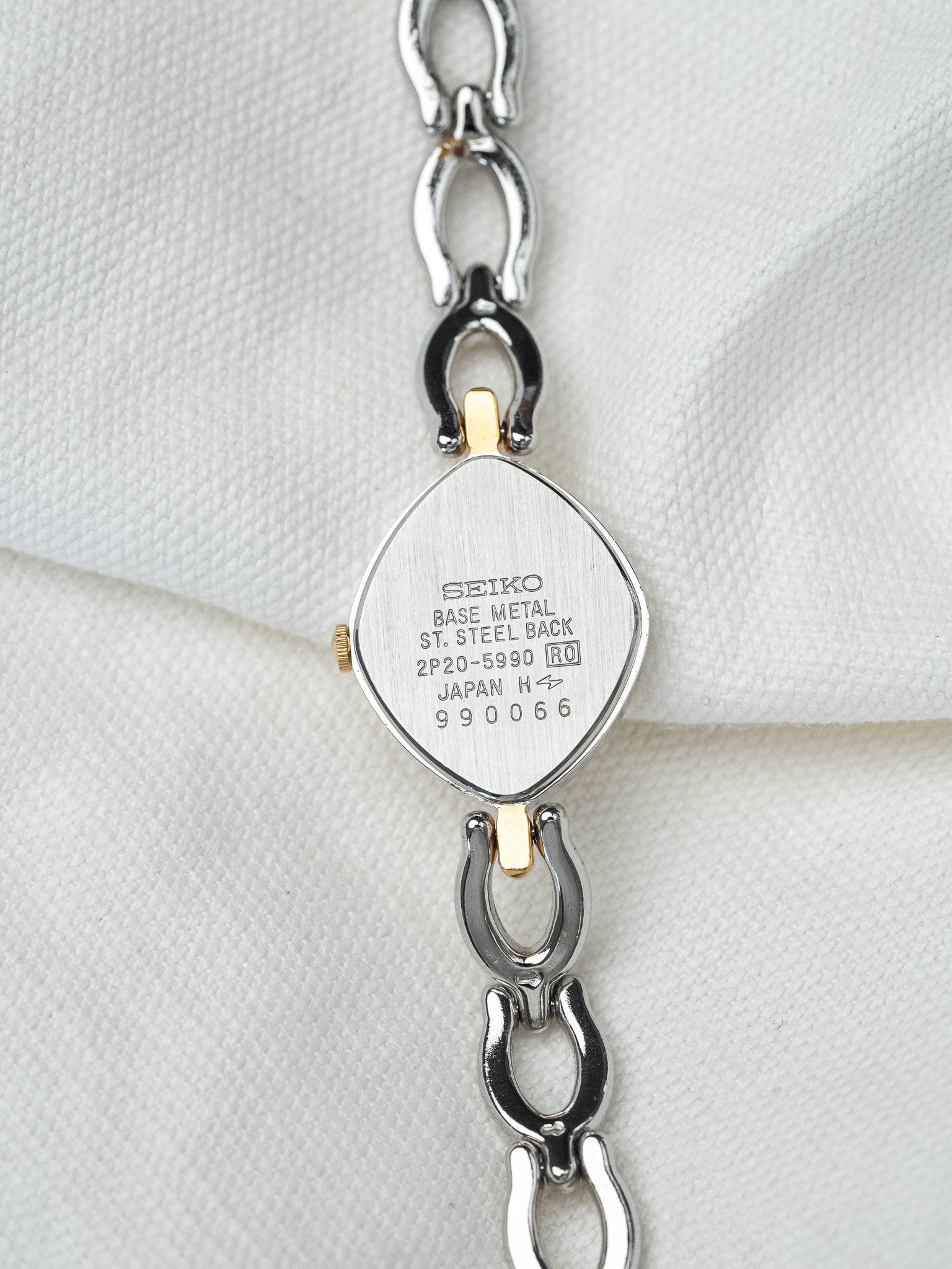 Seiko vintage watch back with steel case and gold accents on white fabric