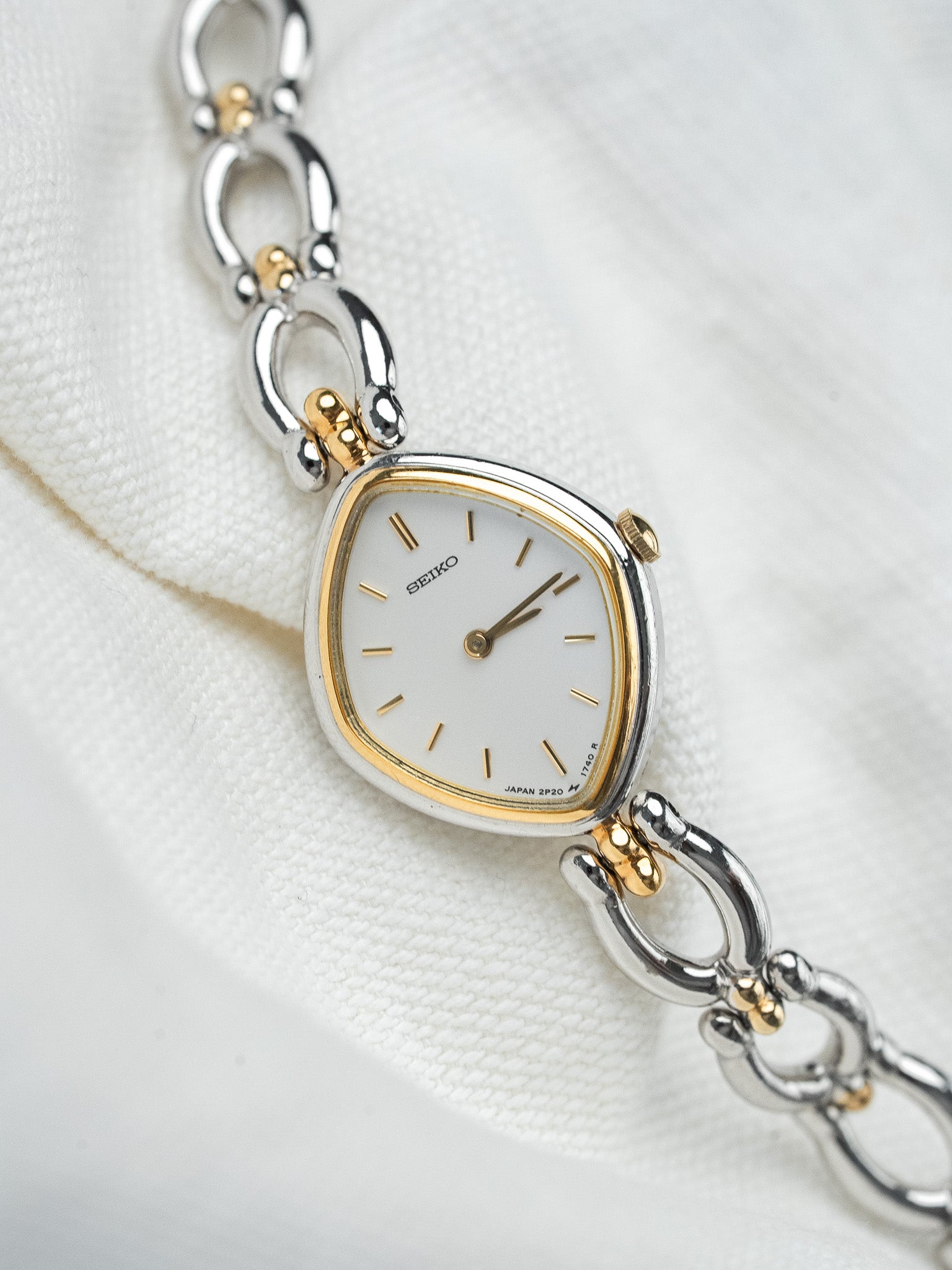 Seiko vintage watch with white dial, gold accents, and two-tone bracelet on fabric