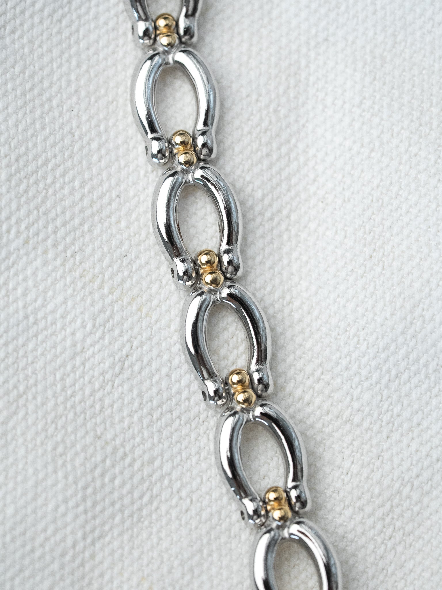 Vintage two-tone bracelet with oval links and gold accents on white fabric