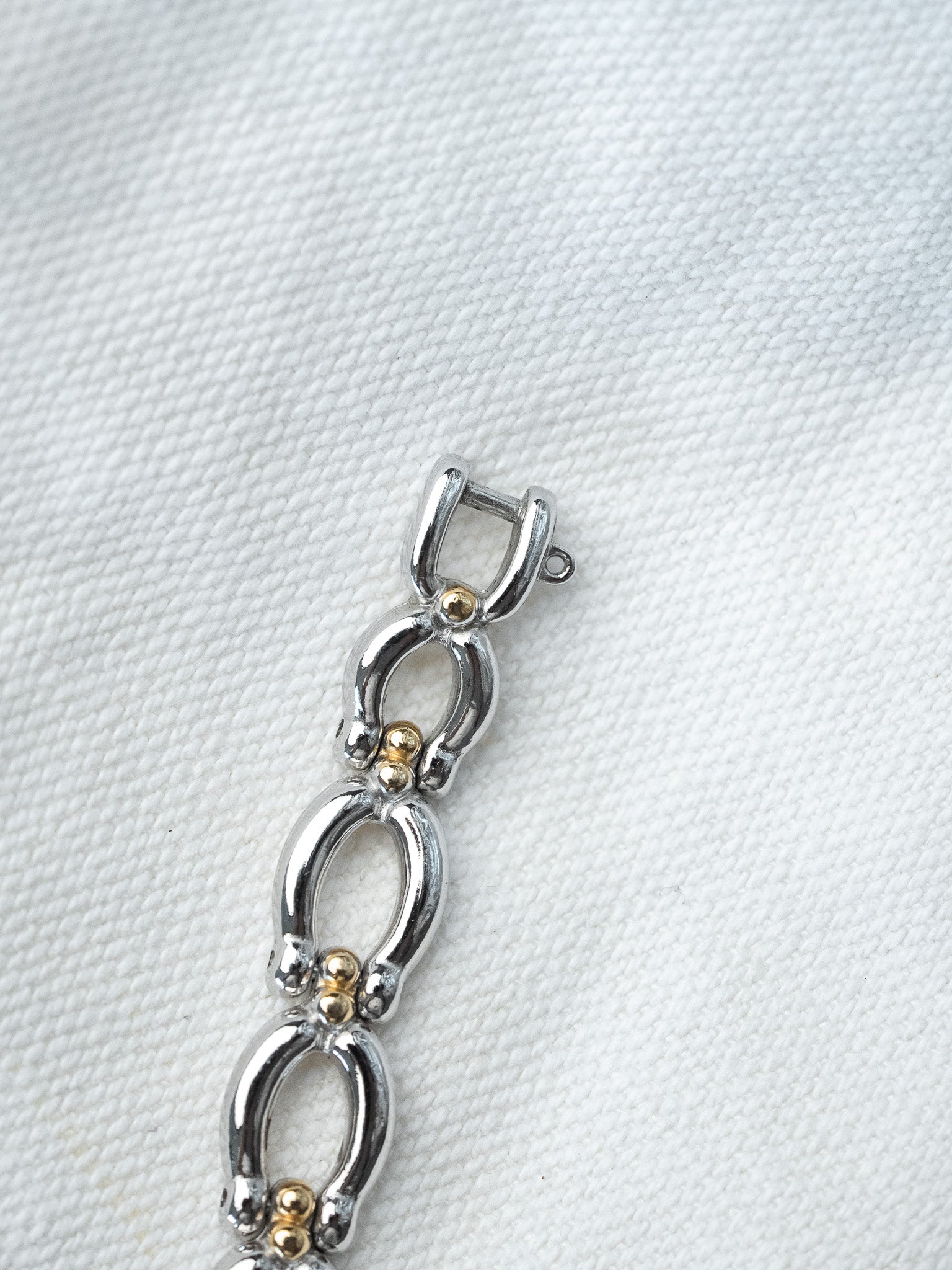 Vintage two-tone bracelet with oval links and gold accents on white fabric