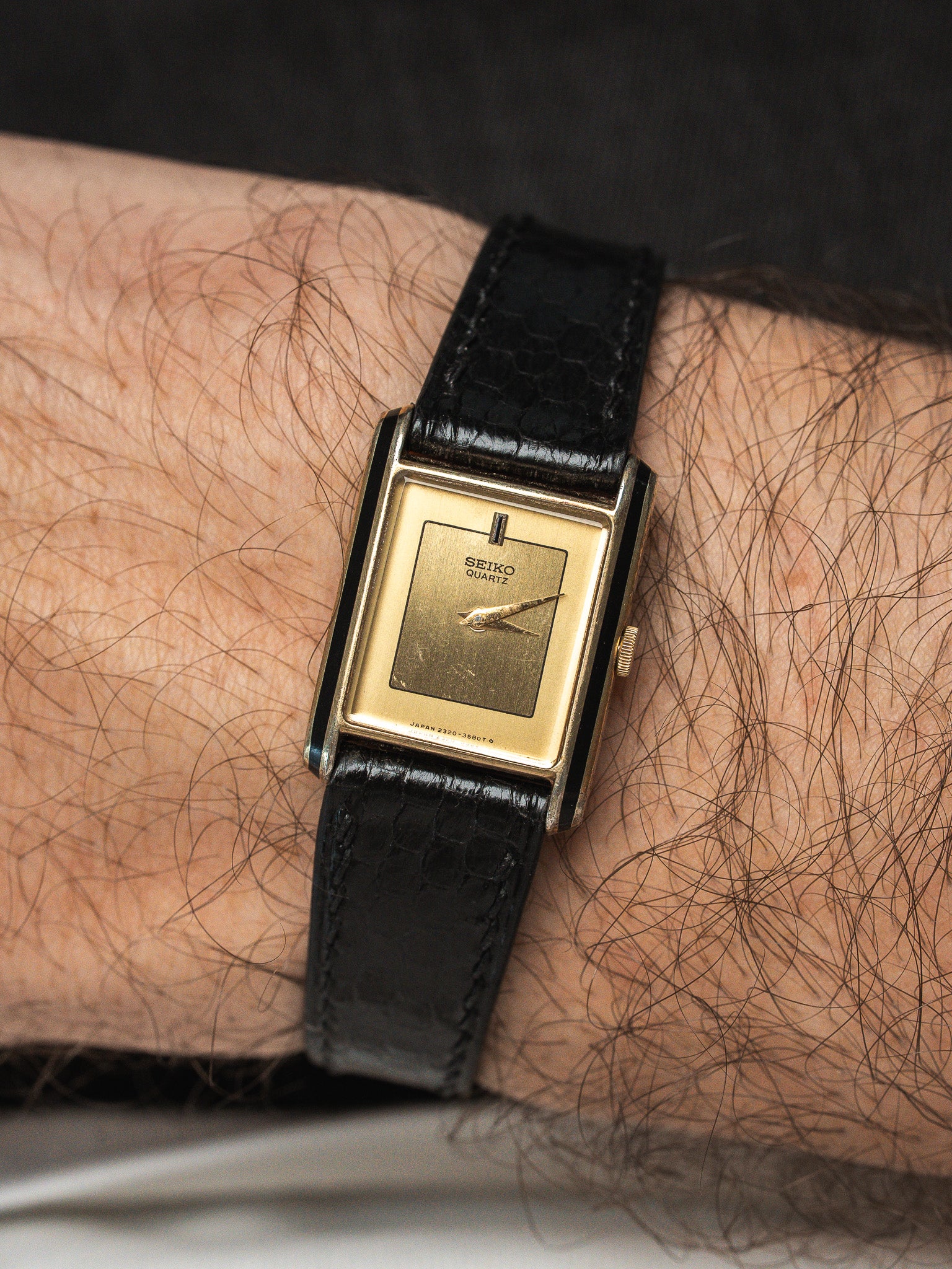 Seiko Quartz vintage watch with gold dial and black leather strap on wrist