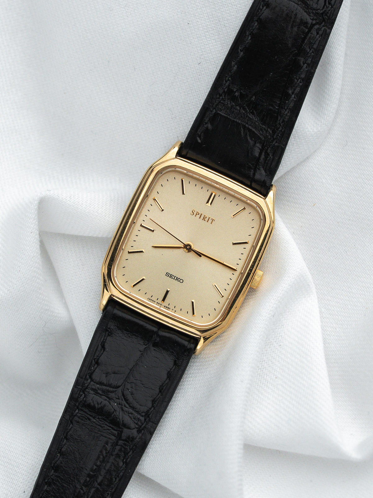 Montre Seiko Spirit vintage, boîtier rectangulaire plaqué or, bracelet cuir noir, fond blanc