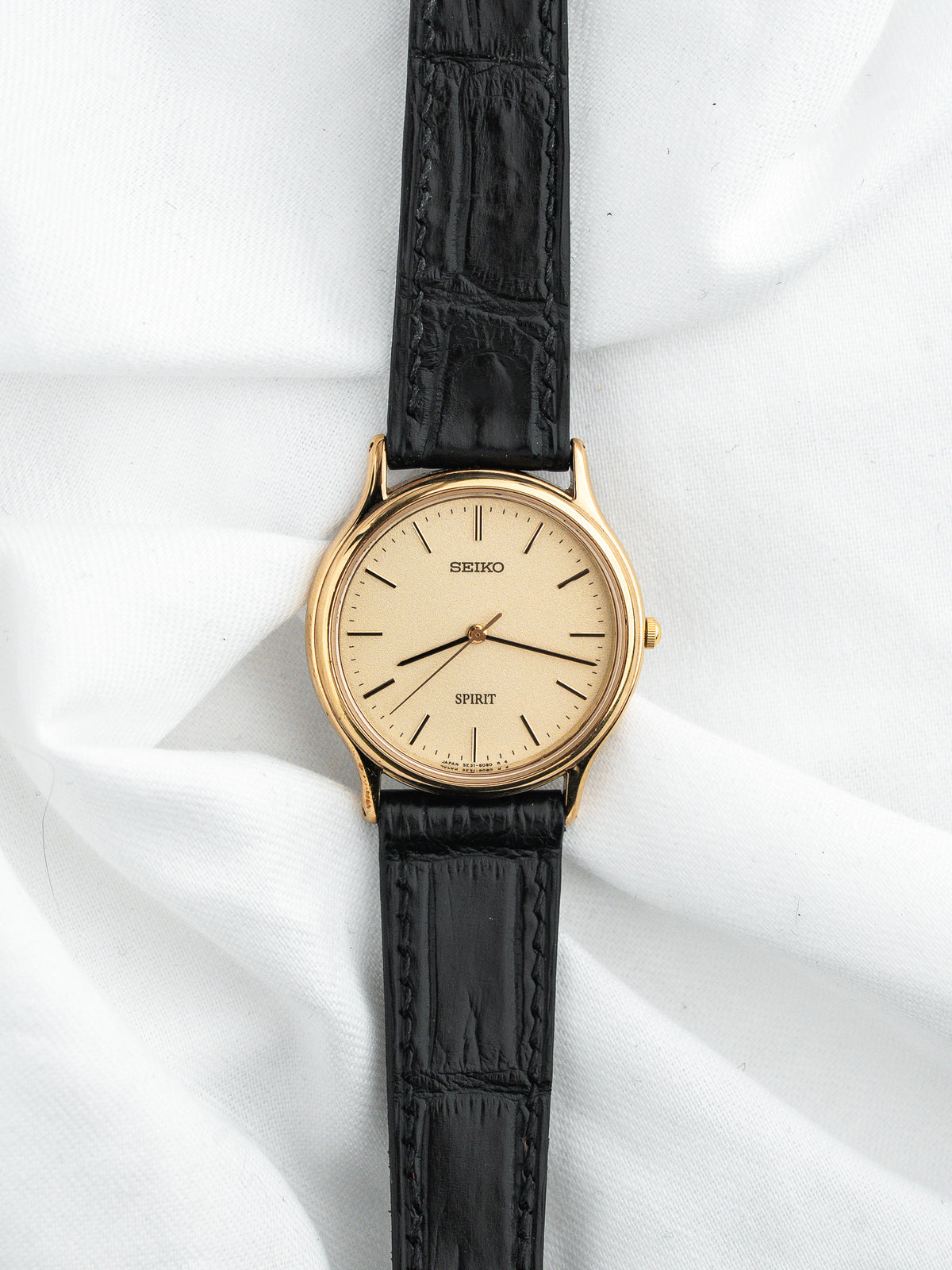 Montre Seiko Spirit vintage, boîtier doré, cadran champagne et bracelet cuir noir