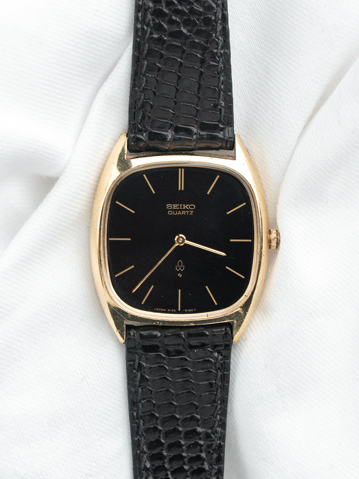 Montre Seiko Quartz vintage, boîtier doré rectangulaire, cadran noir et bracelet cuir noir