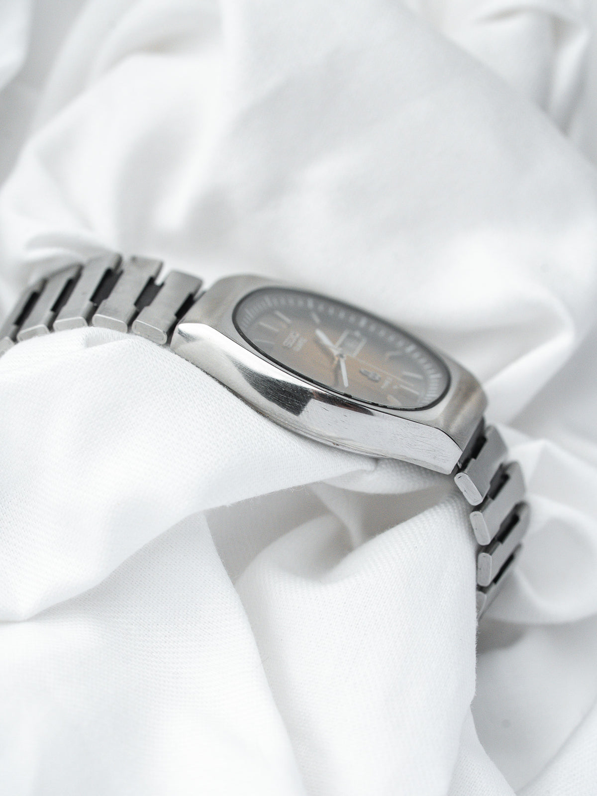 Vintage Omega watch with silver-toned case and bracelet, resting on white fabric