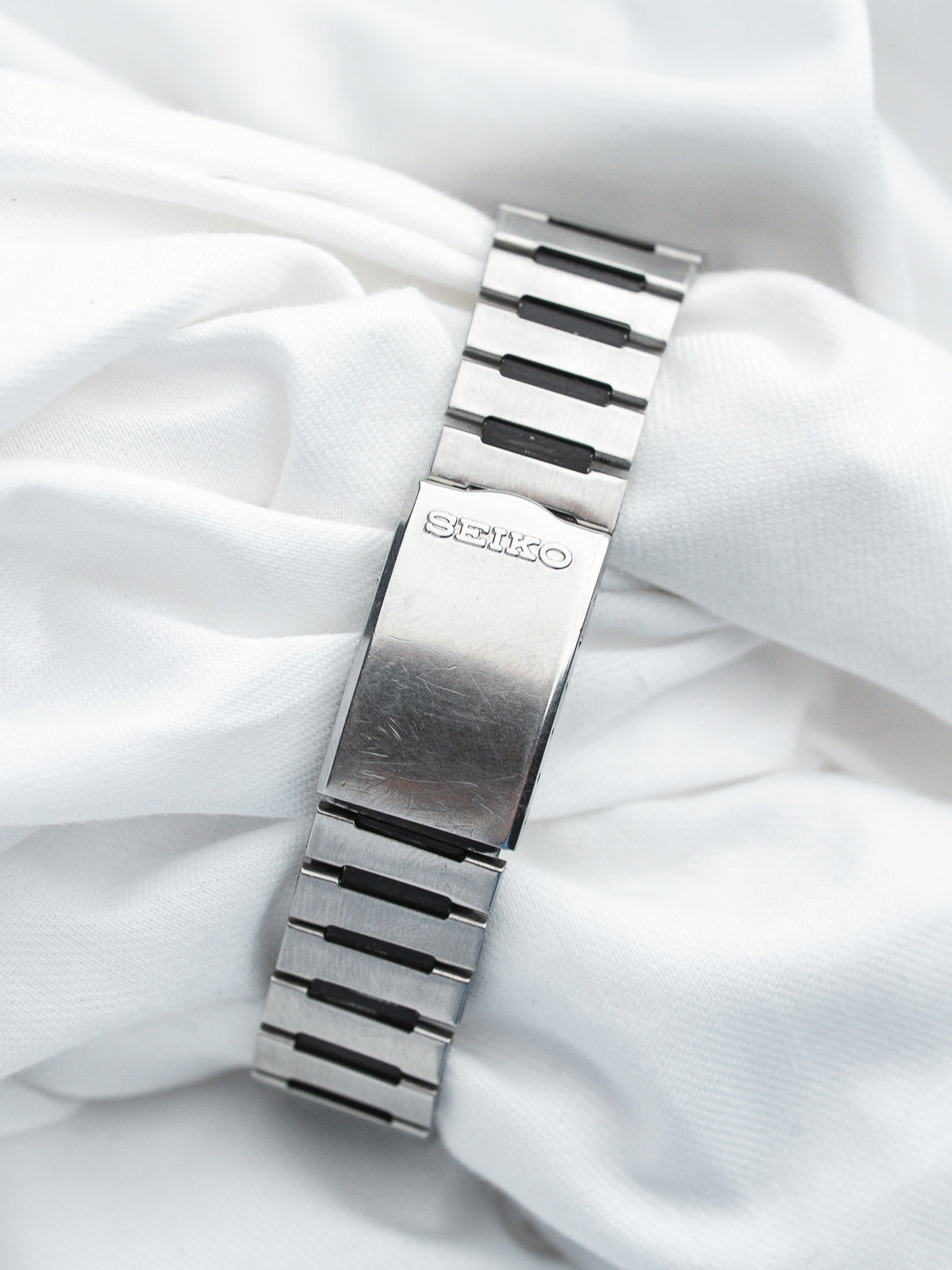 Seiko vintage watch bracelet in stainless steel with black accents on white fabric