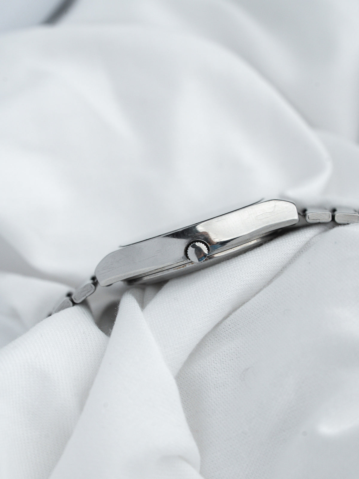 Vintage Cartier watch side profile, stainless steel case, on white fabric background