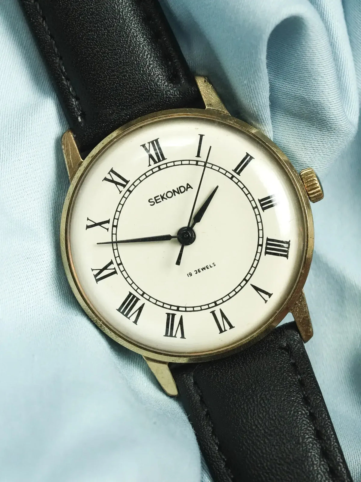 Vintage Sekonda watch with gold case, white dial, Roman numerals, black leather strap