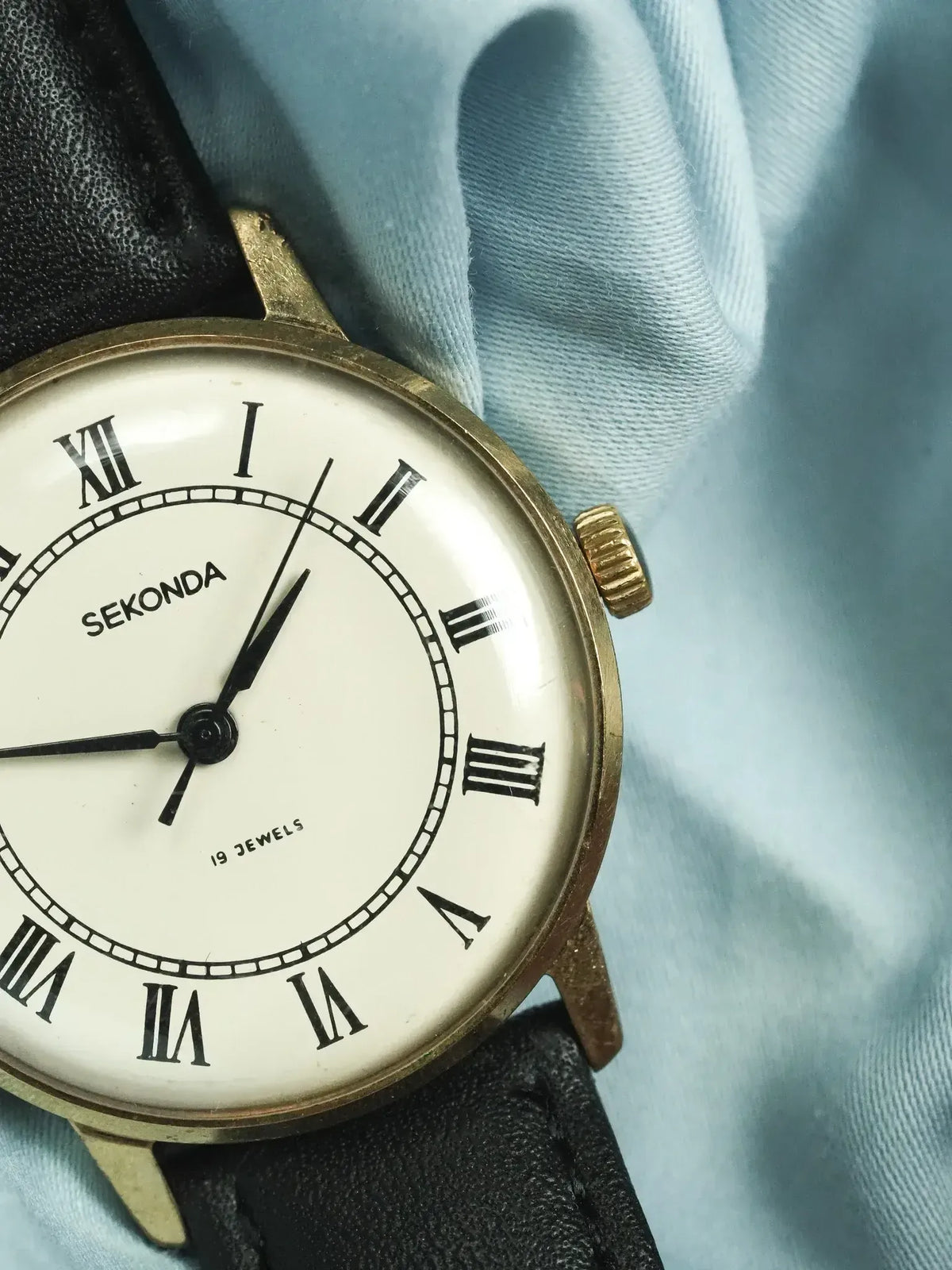 Vintage Sekonda watch with white dial, Roman numerals, and black leather strap
