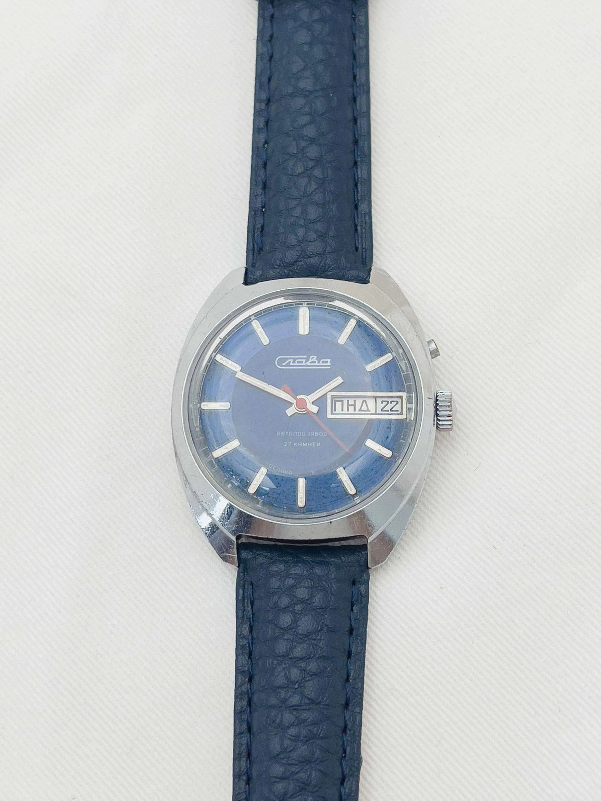 Vintage Slava watch with blue dial, steel case, and dark leather strap