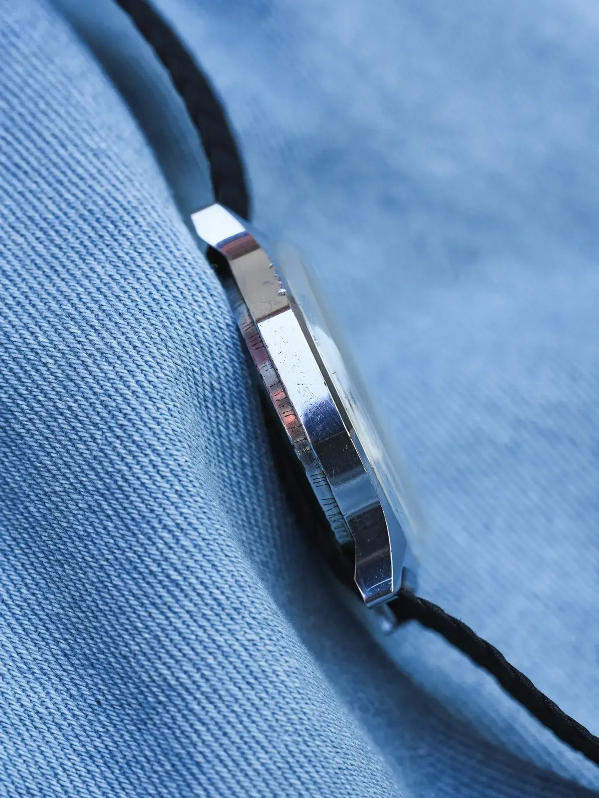 Vintage Omega Constellation watch with steel case and black strap on denim