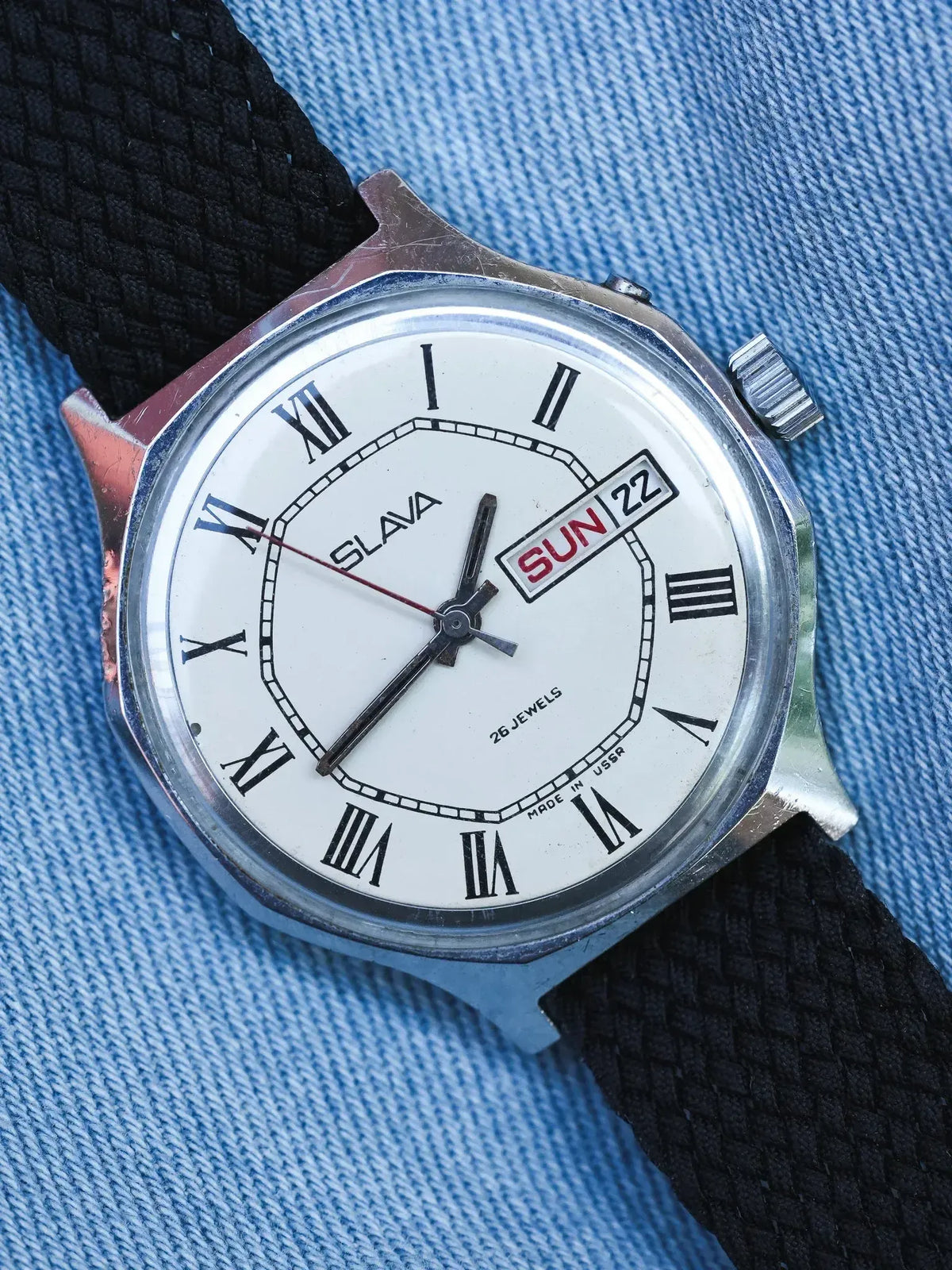Slava vintage watch with white dial, Roman numerals, day-date, black fabric strap on denim