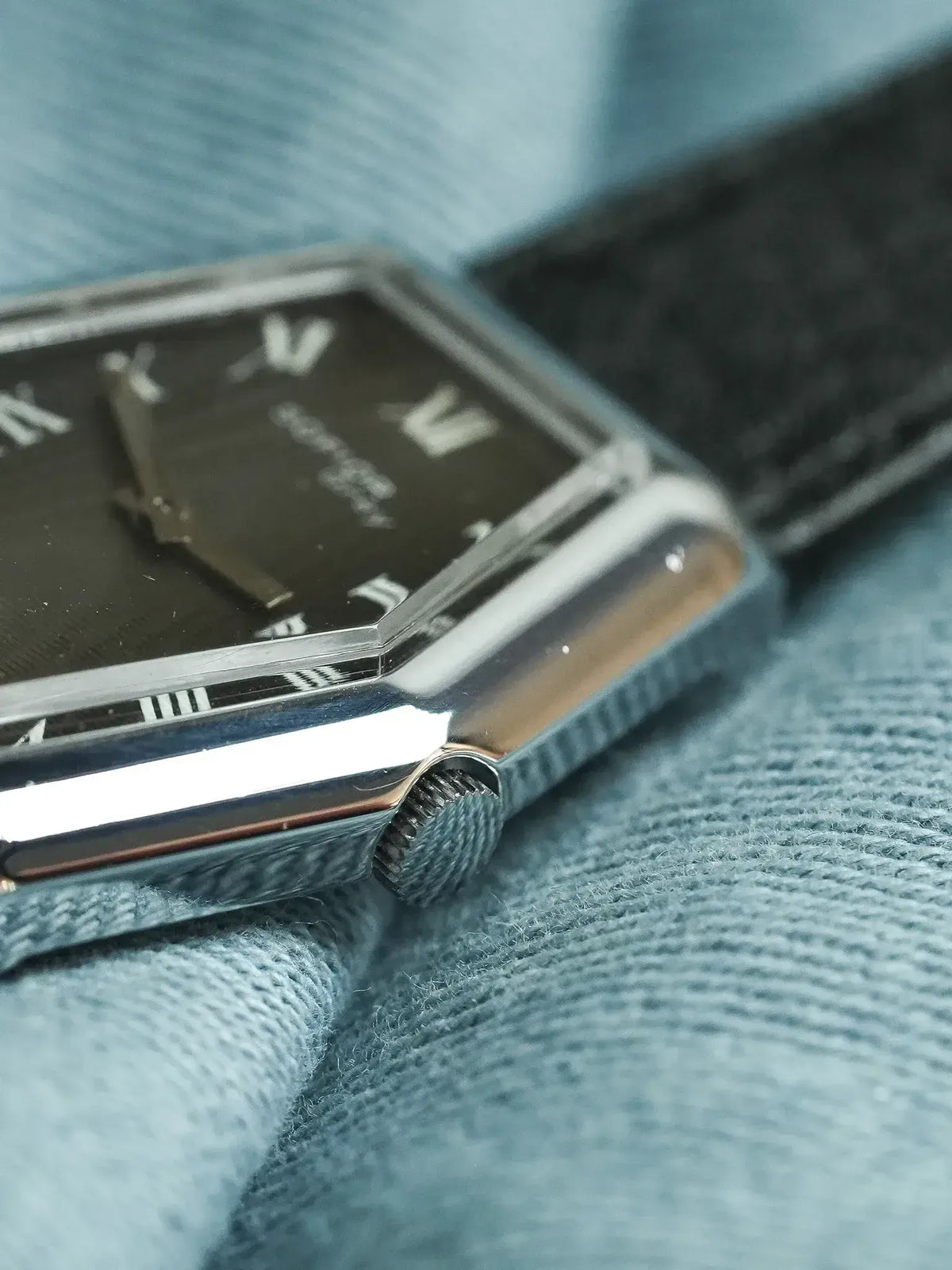 Cartier Tank vintage watch with black dial, silver case, and textured strap on denim