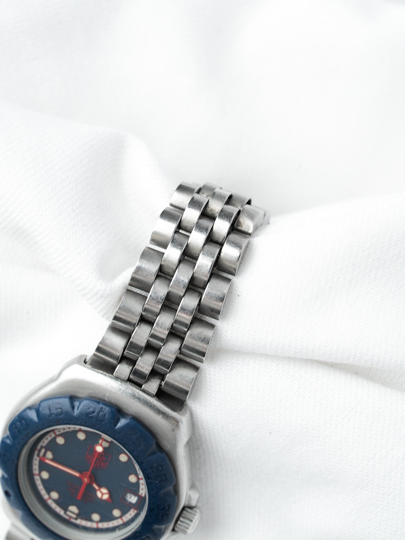 TAG Heuer vintage watch with blue dial, red hands, and steel bracelet