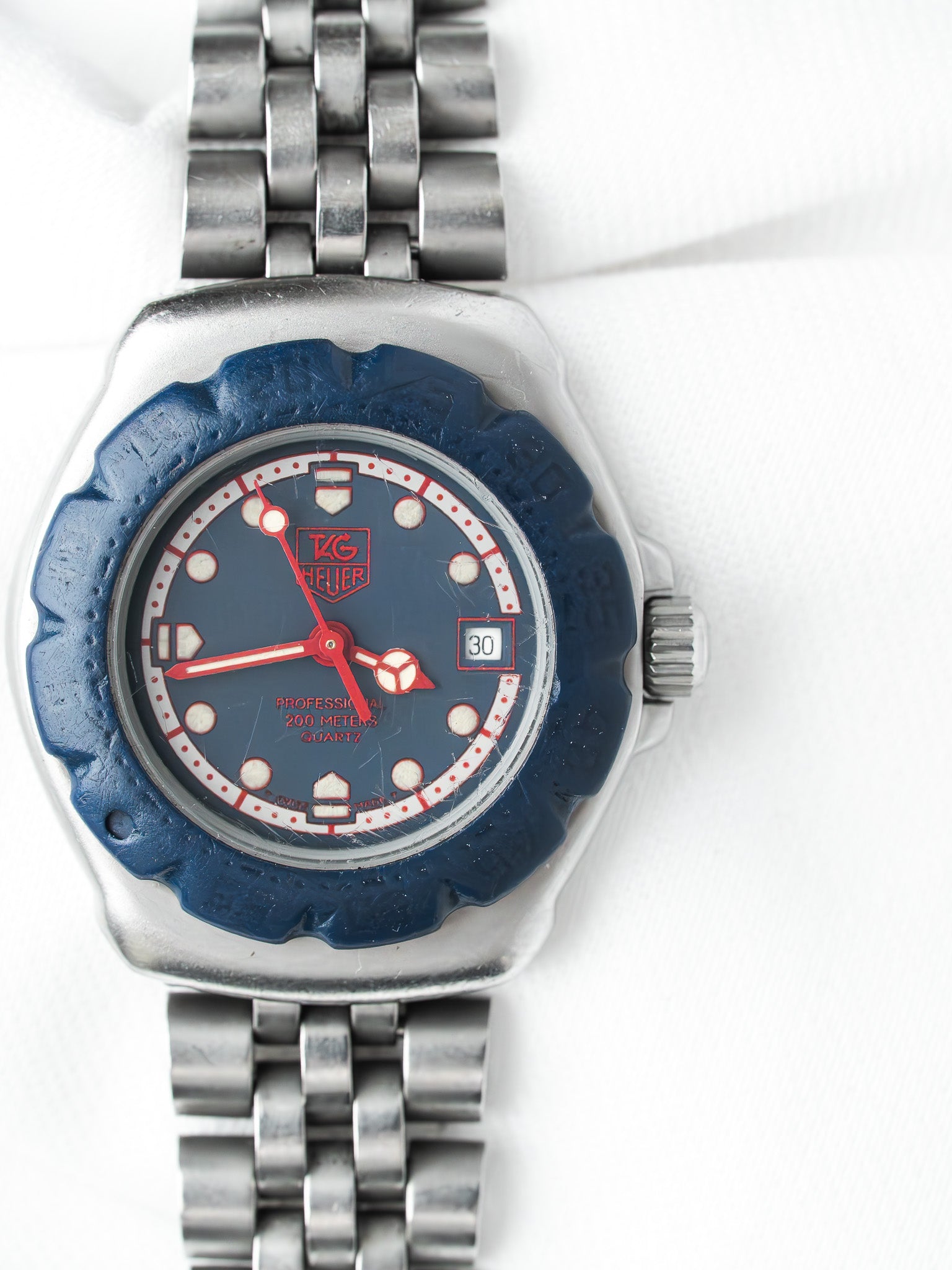 TAG Heuer vintage watch with blue dial, red accents, and steel bracelet