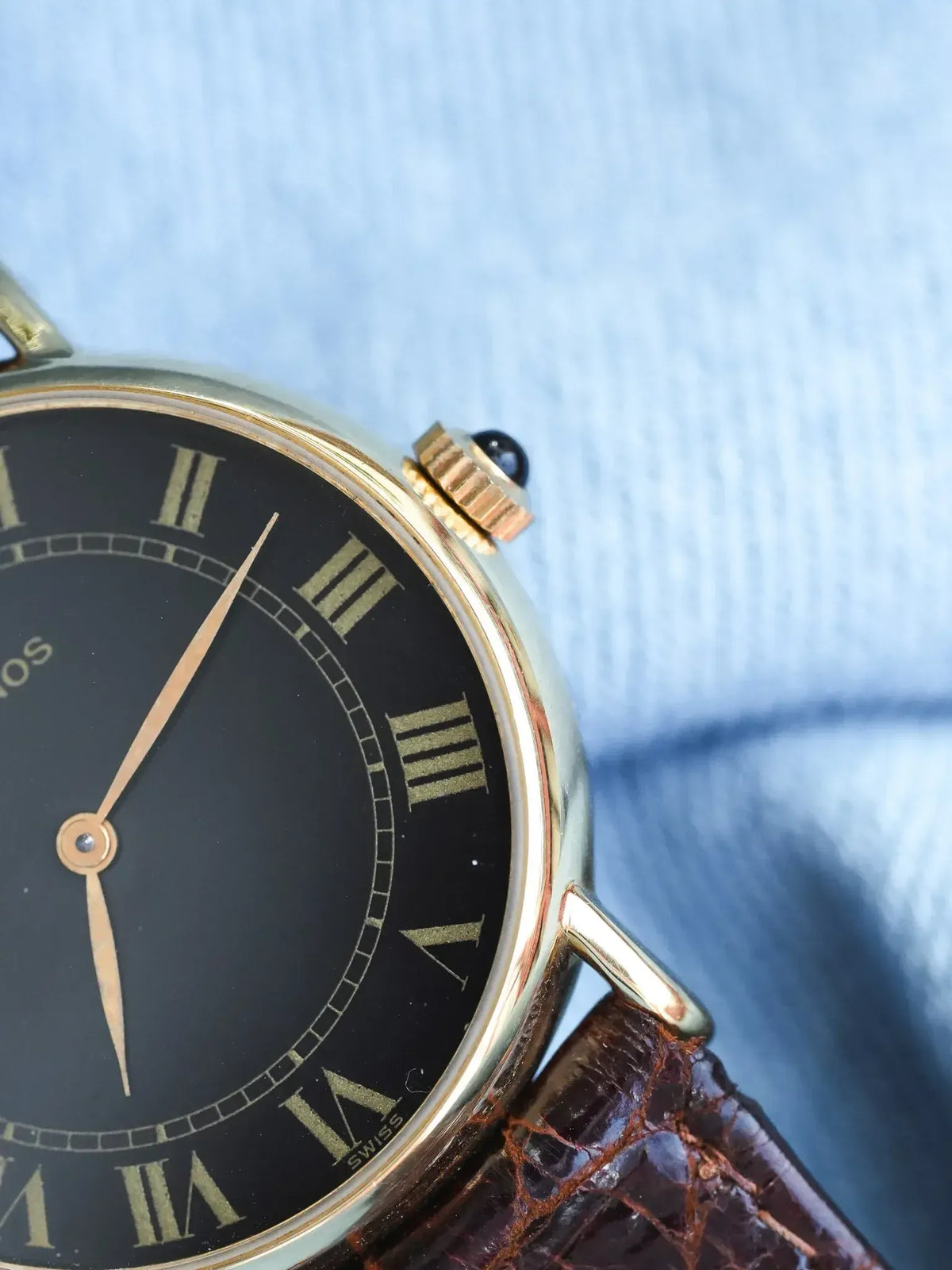 Vintage Universal Genève watch with gold case, black dial, Roman numerals, brown leather strap