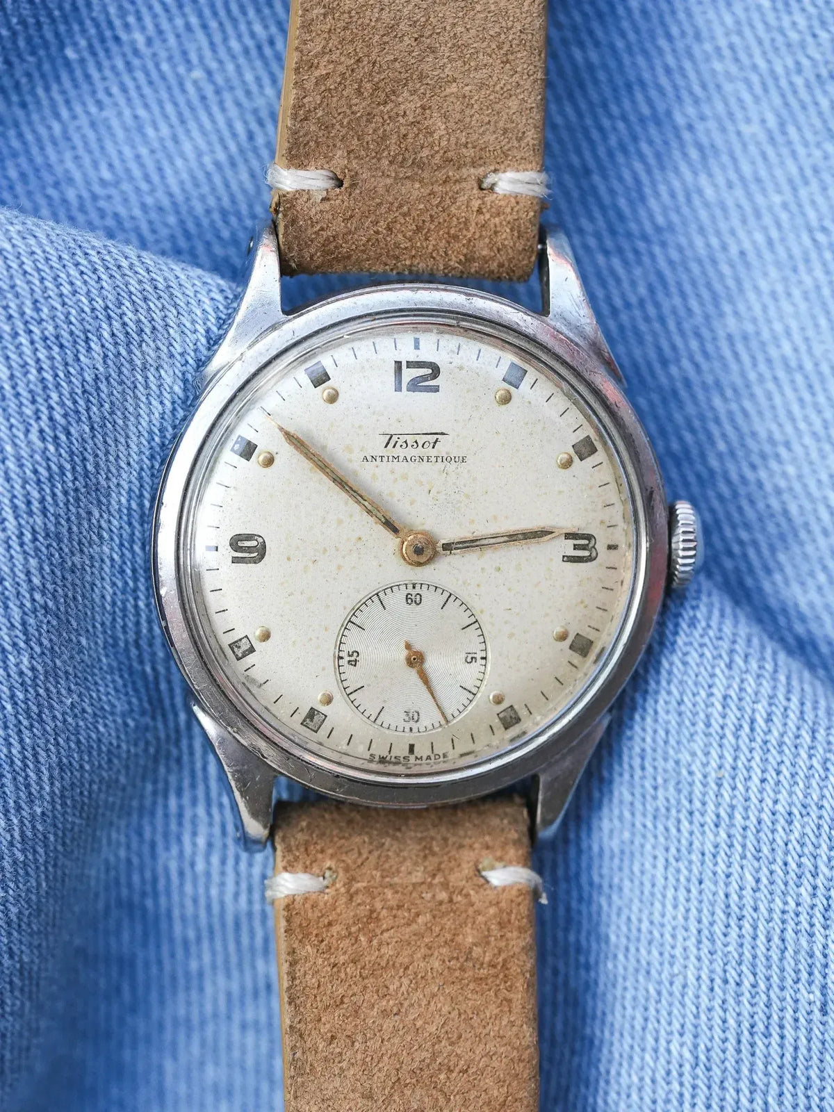 Vintage Tissot Antimagnetique watch with cream dial, brown leather strap on denim