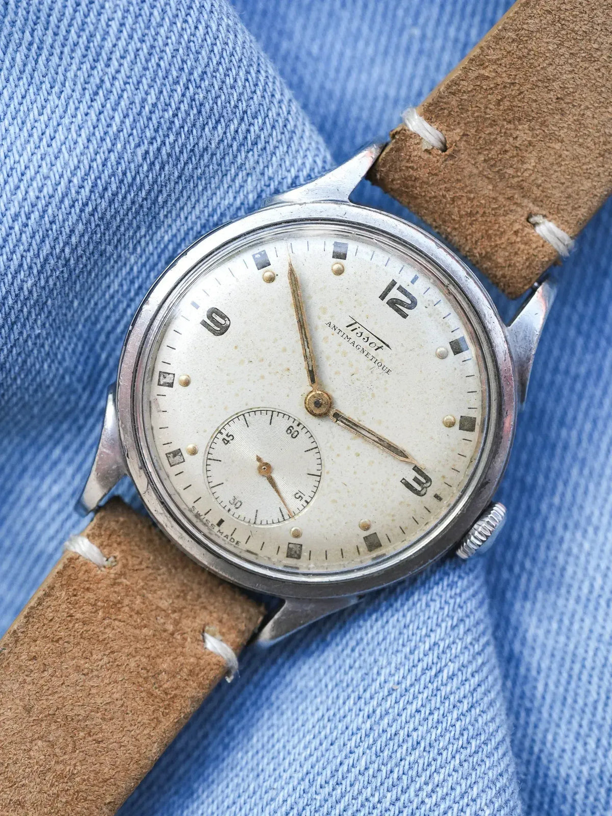Tissot vintage watch with cream dial, brown leather strap, on denim background