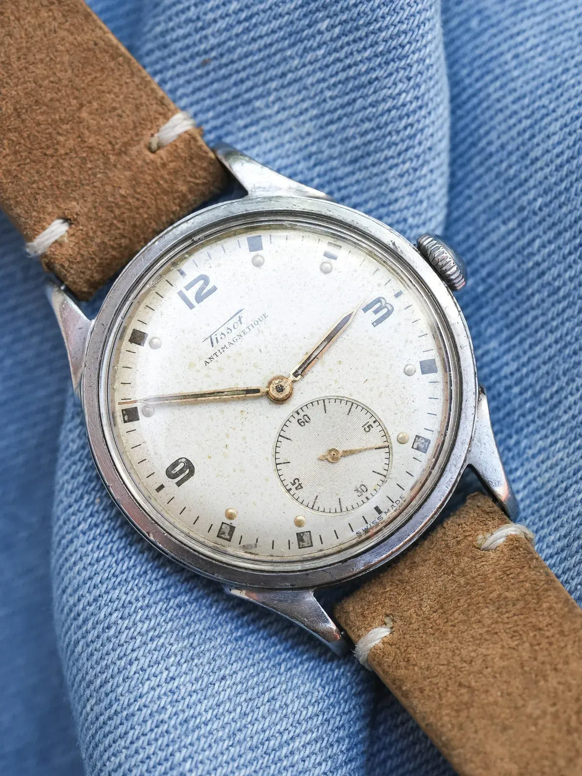 Tissot vintage antimagnetic watch with cream dial, brown leather strap on denim