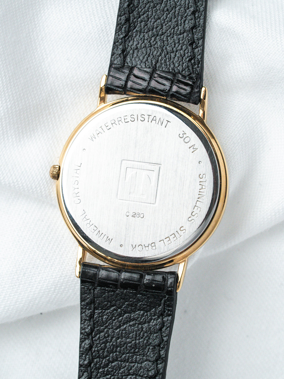 Vintage watch with gold case, black textured strap, stainless steel back, water-resistant 30M