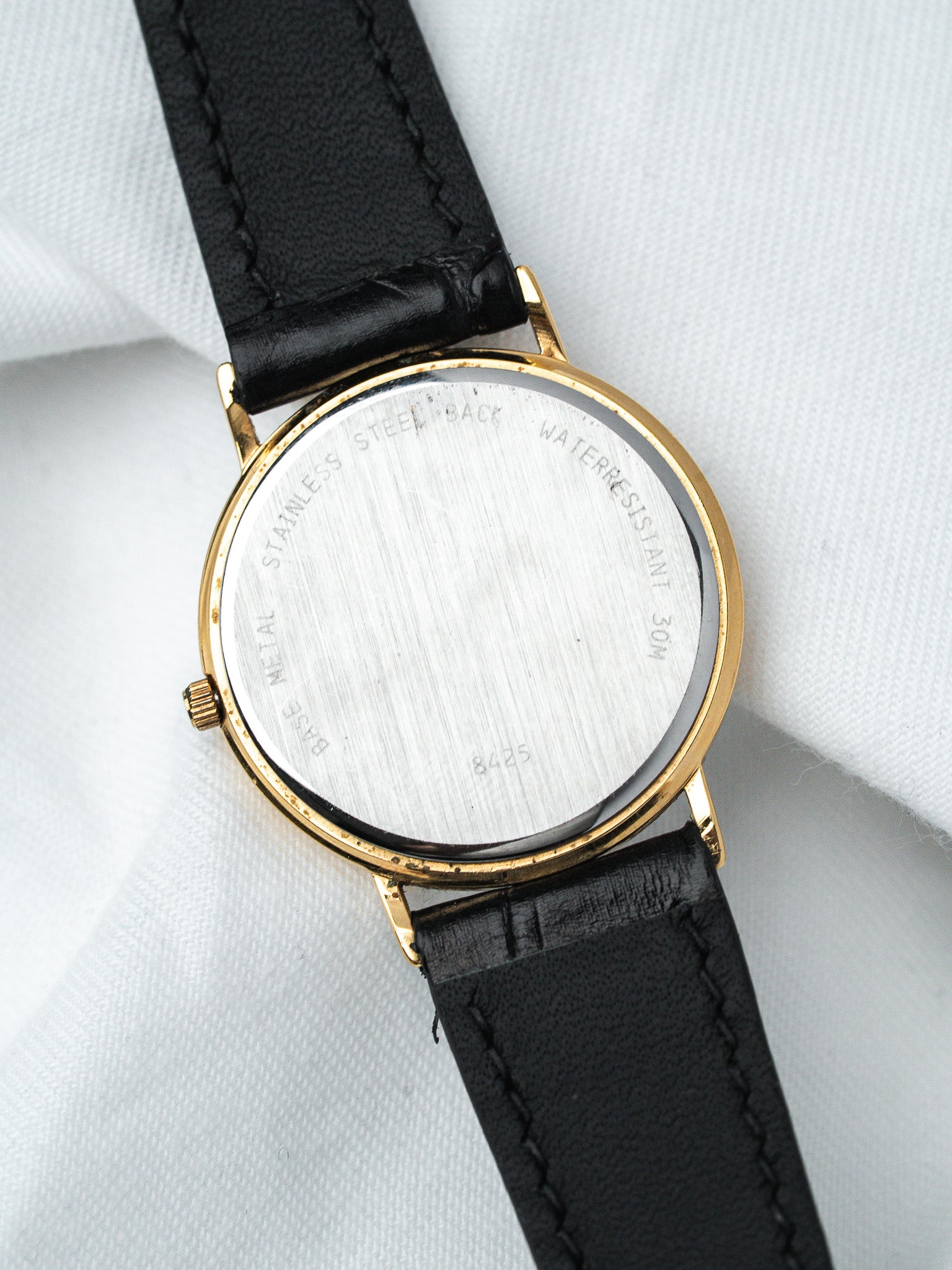 Vintage watch with gold case, black leather strap, stainless steel back, water resistant 30M