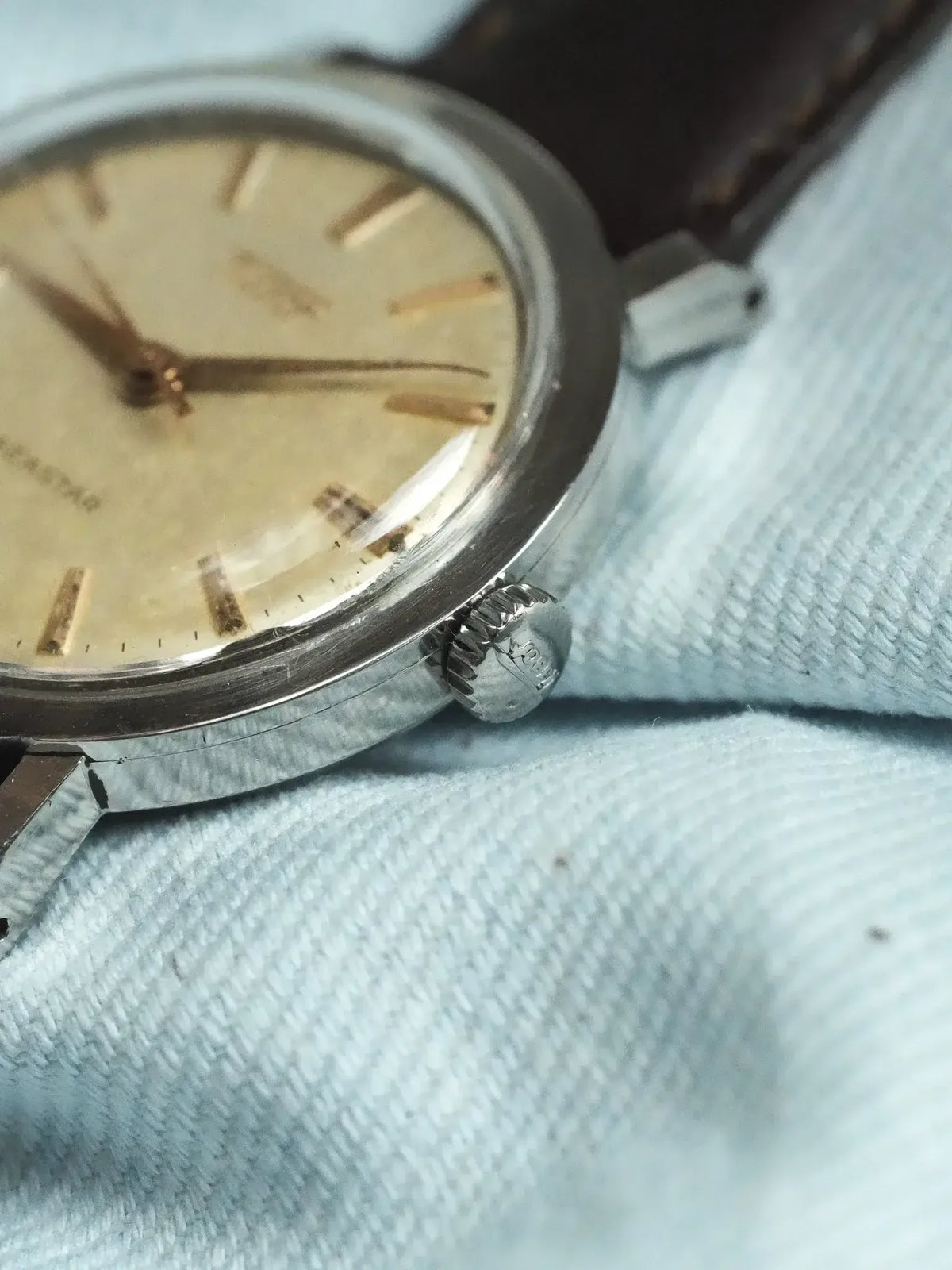Vintage Universal Genève wristwatch with cream dial, steel case, brown leather strap on fabric