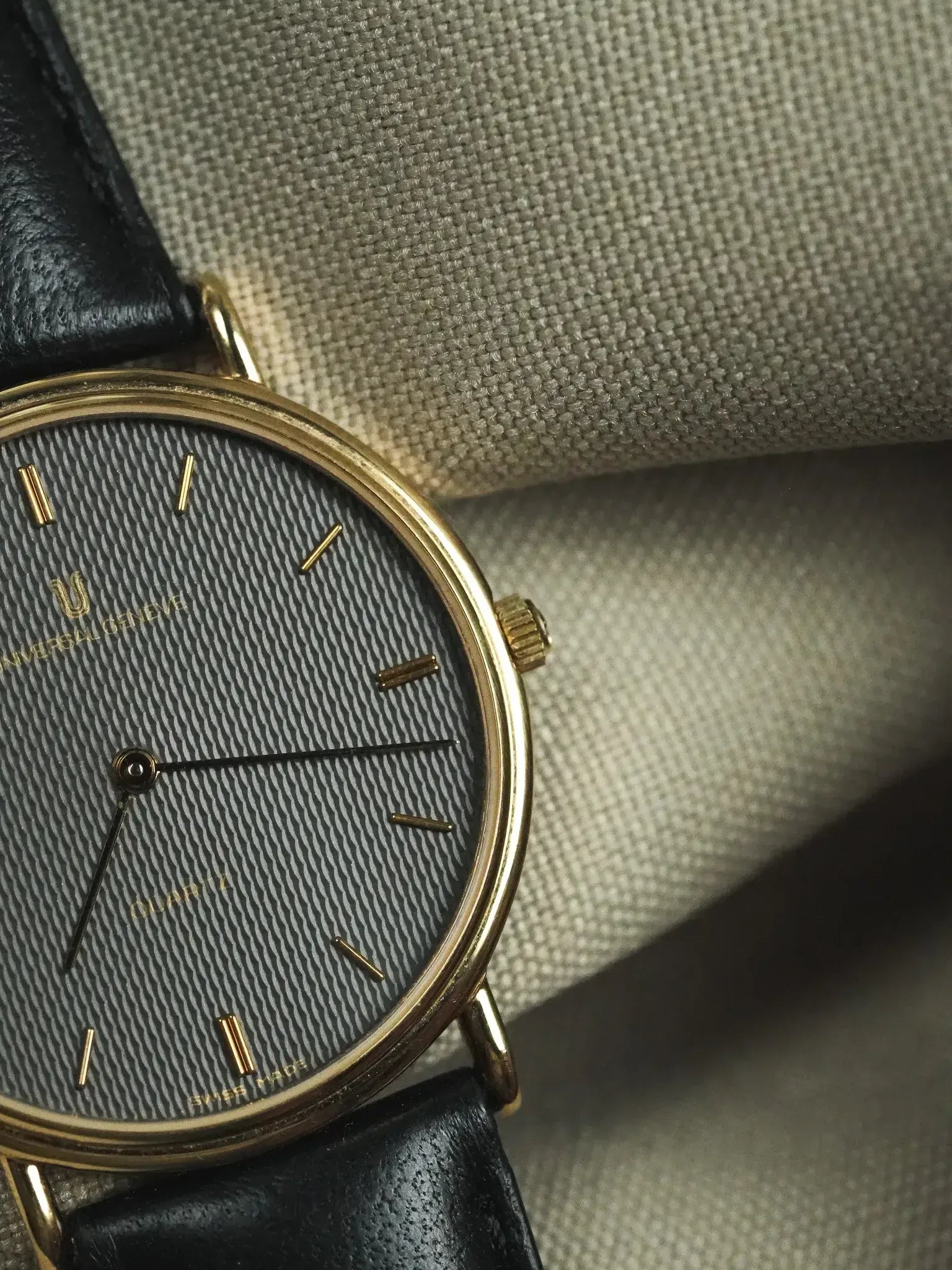 Universal Genève vintage watch with gold case, grey textured dial, black leather strap