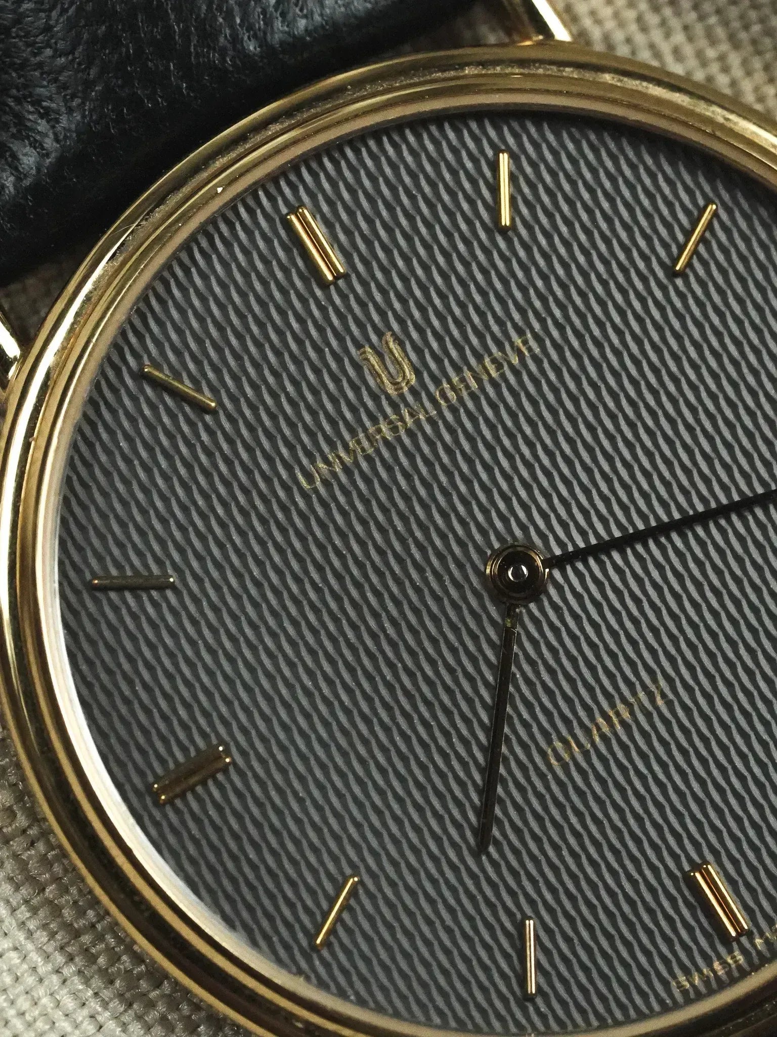 Universal Genève vintage quartz watch with textured grey dial, gold markers, and gold case