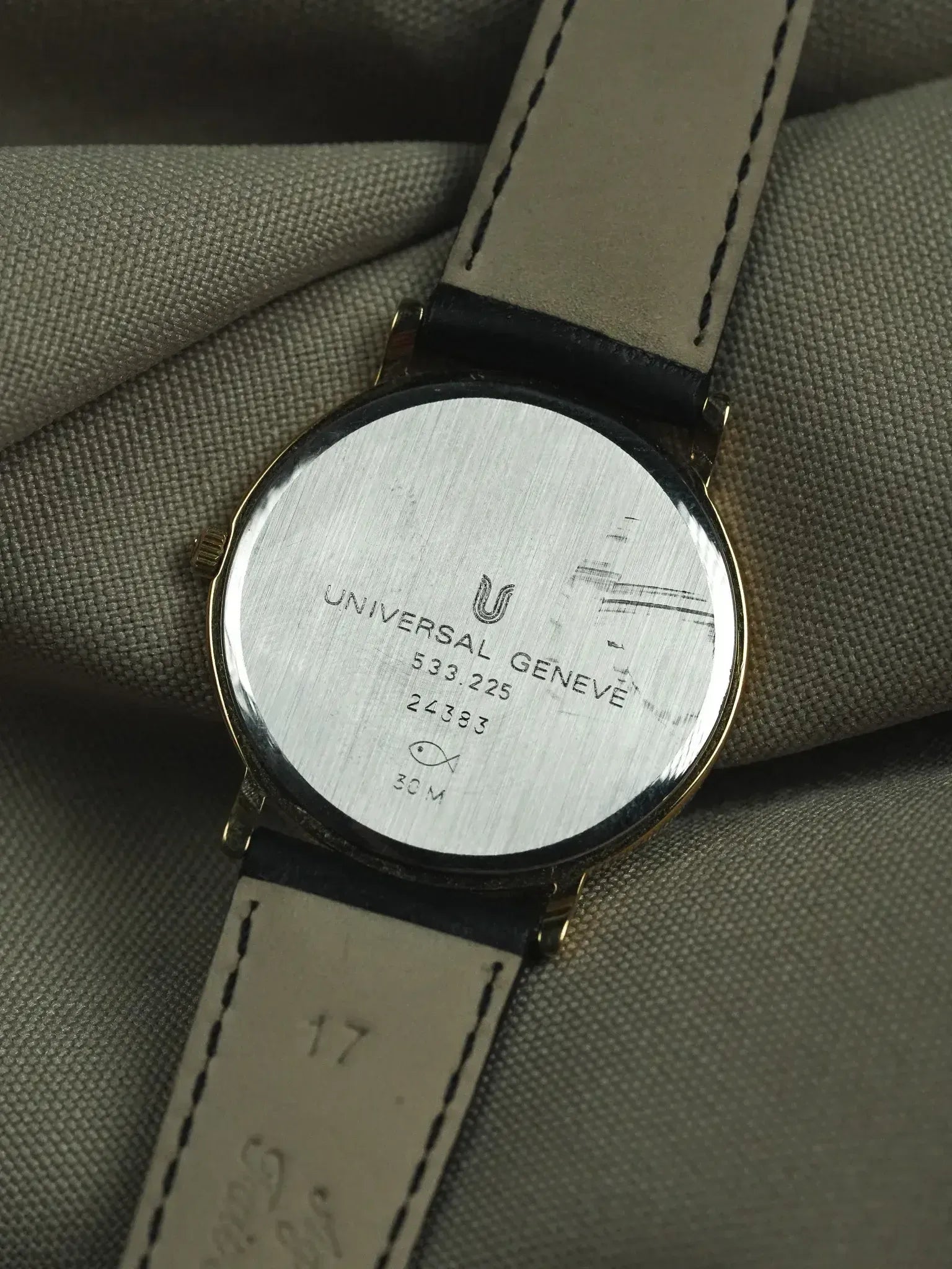 Universal Geneve vintage watch back, gold case, leather strap, engraved details visible