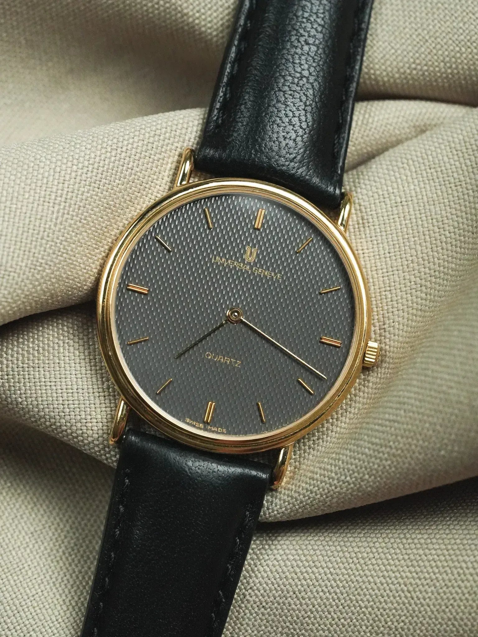 Universal Genève vintage quartz watch, gold case, black textured dial, black leather strap