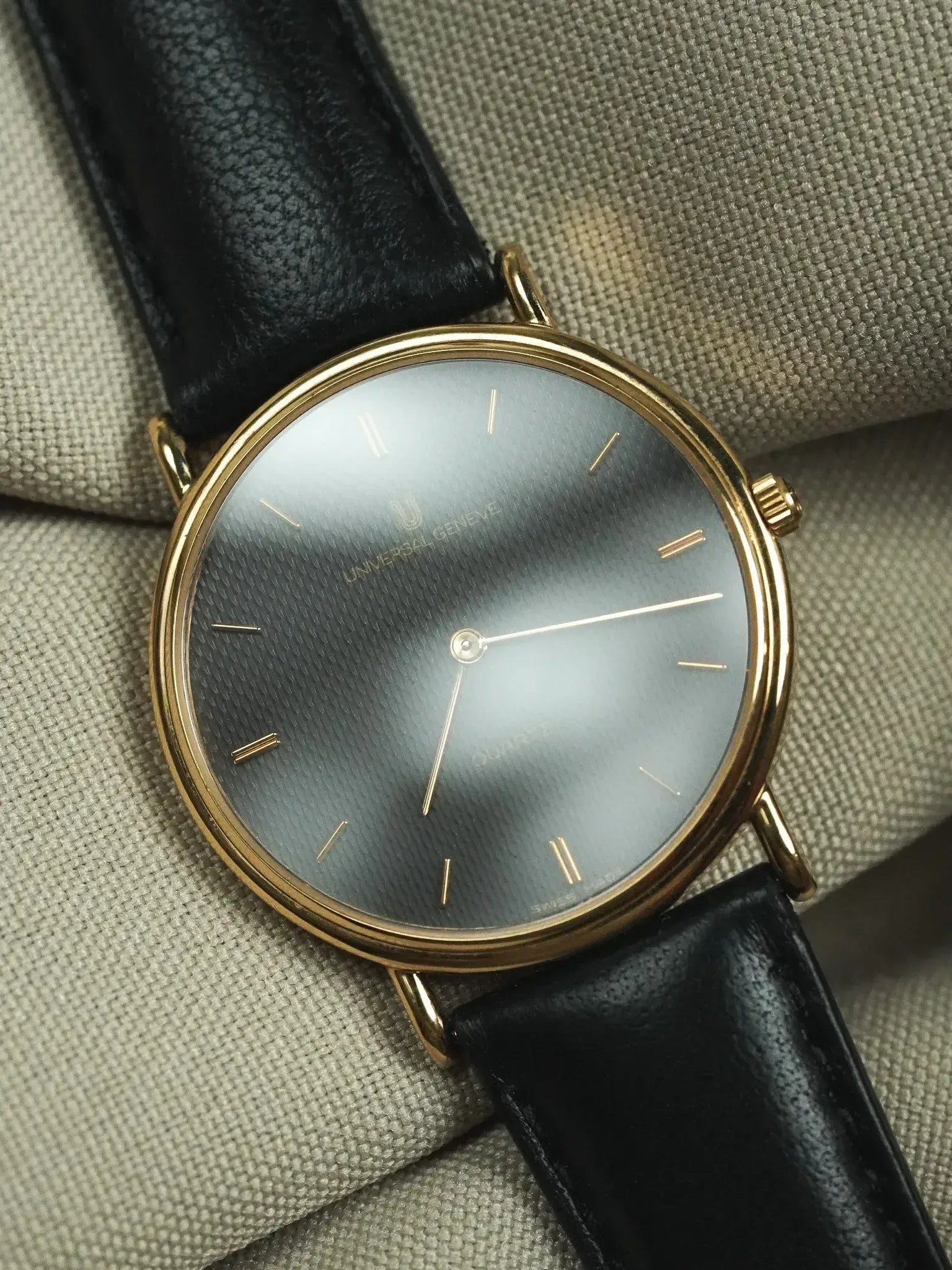 Universal Genève vintage watch with gold case, grey textured dial, black leather strap