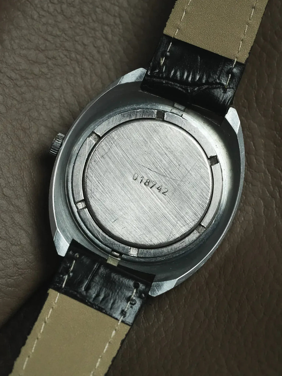 Vintage watch with brushed steel case back and black leather strap
