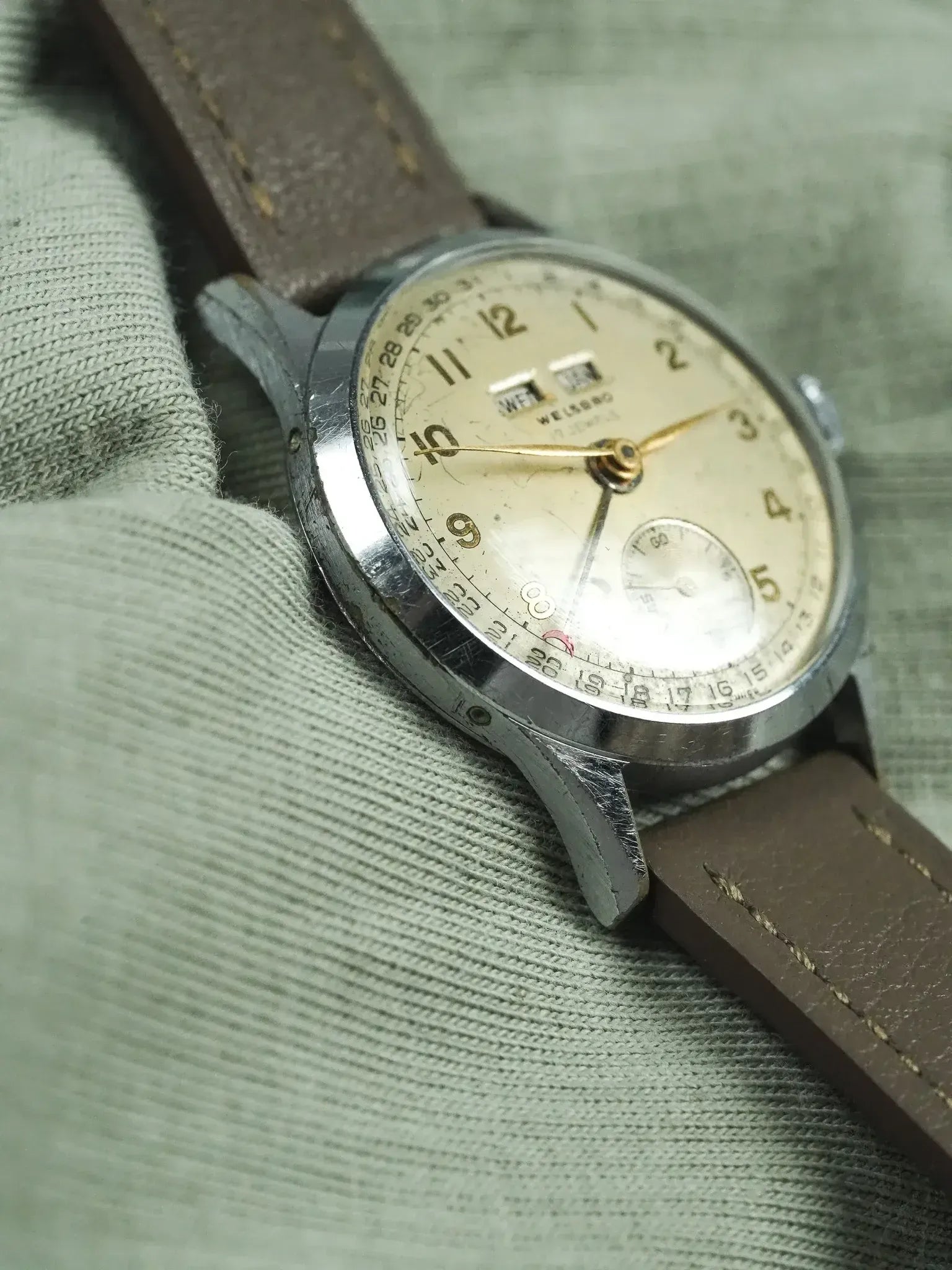 Vintage Welsero wristwatch with cream dial, brown leather strap, and steel case