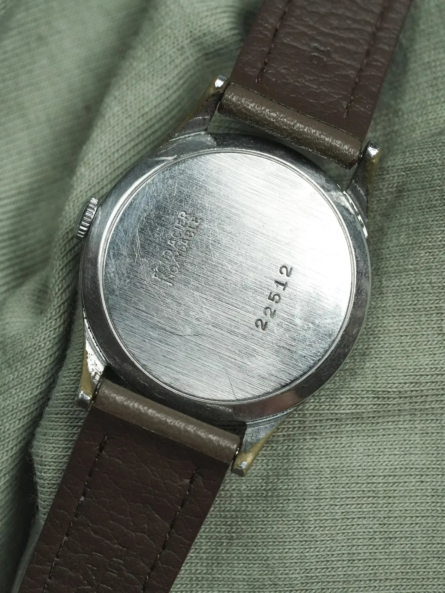 Montre Tissot vintage en acier, fond gravé, bracelet cuir marron sur tissu vert
