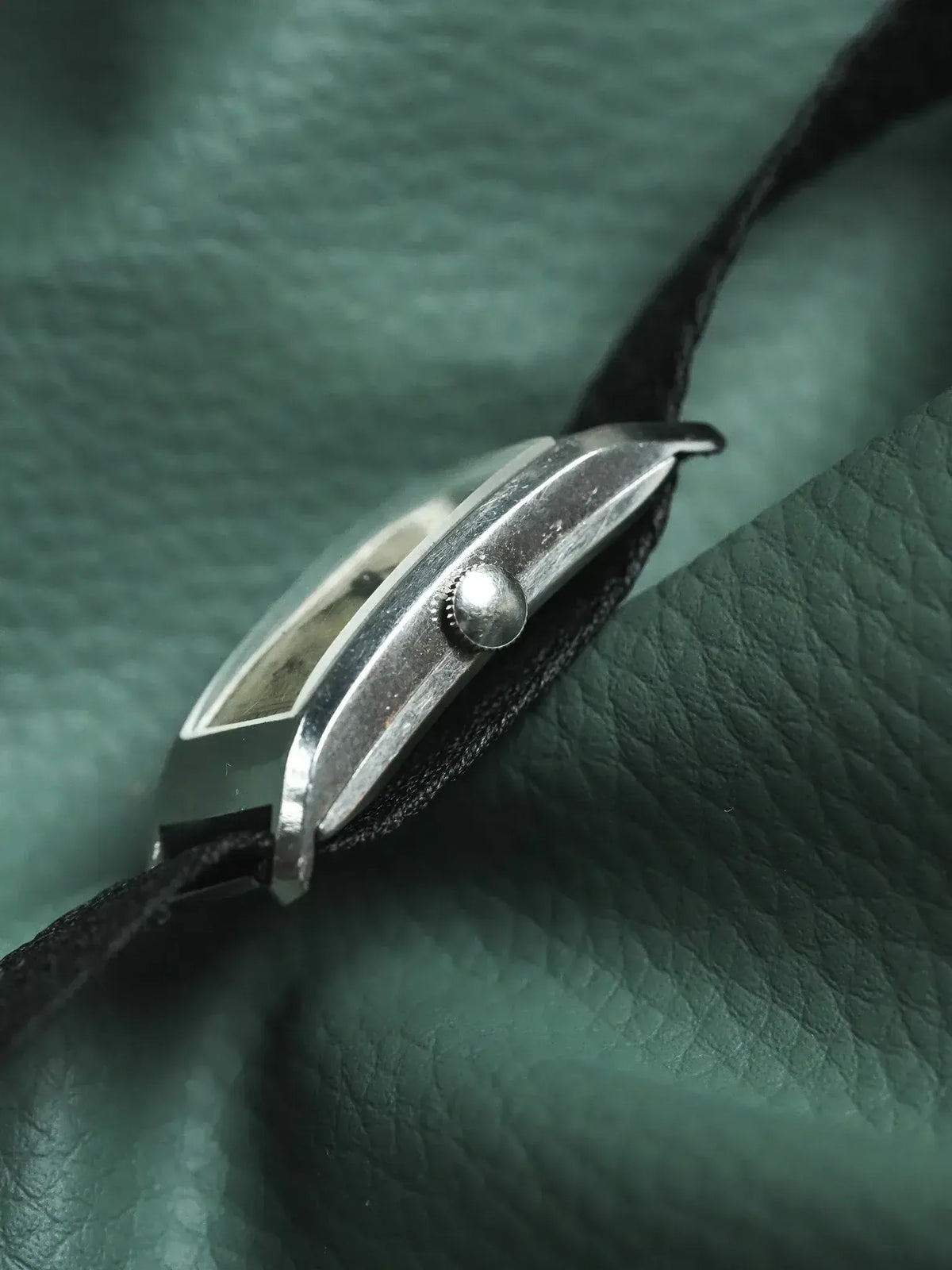Vintage Cartier watch with rectangular case, black strap, on green leather