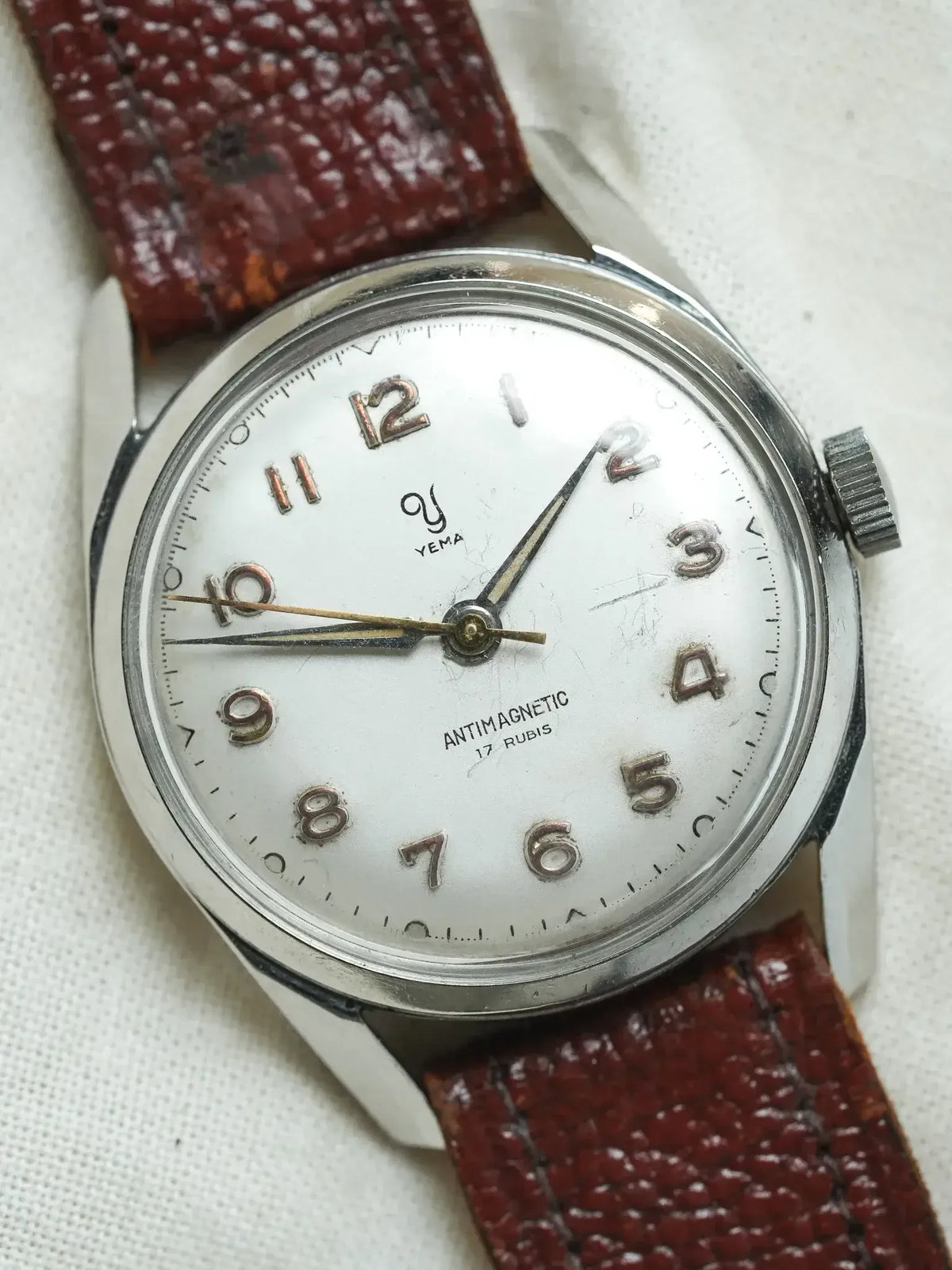 Vintage Yema antimagnetic watch with white dial, steel case, and red textured strap